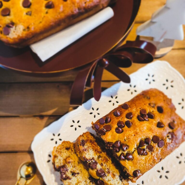 Two banana breads with chocolate and peanut butter chips on a stand and a decorative plate.
