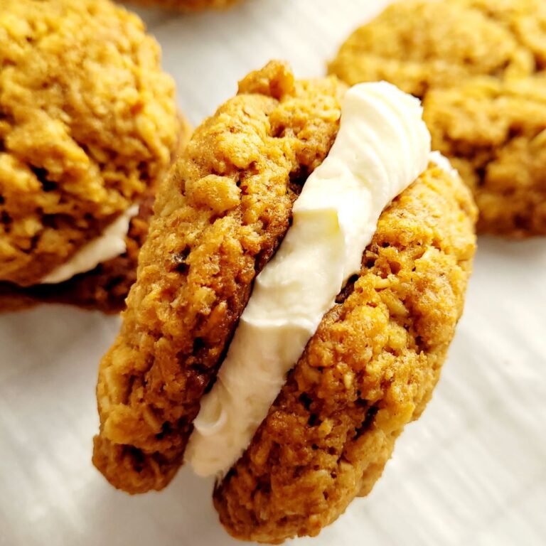 Oatmeal cream pie laying on its side with cream filling on parchment paper.