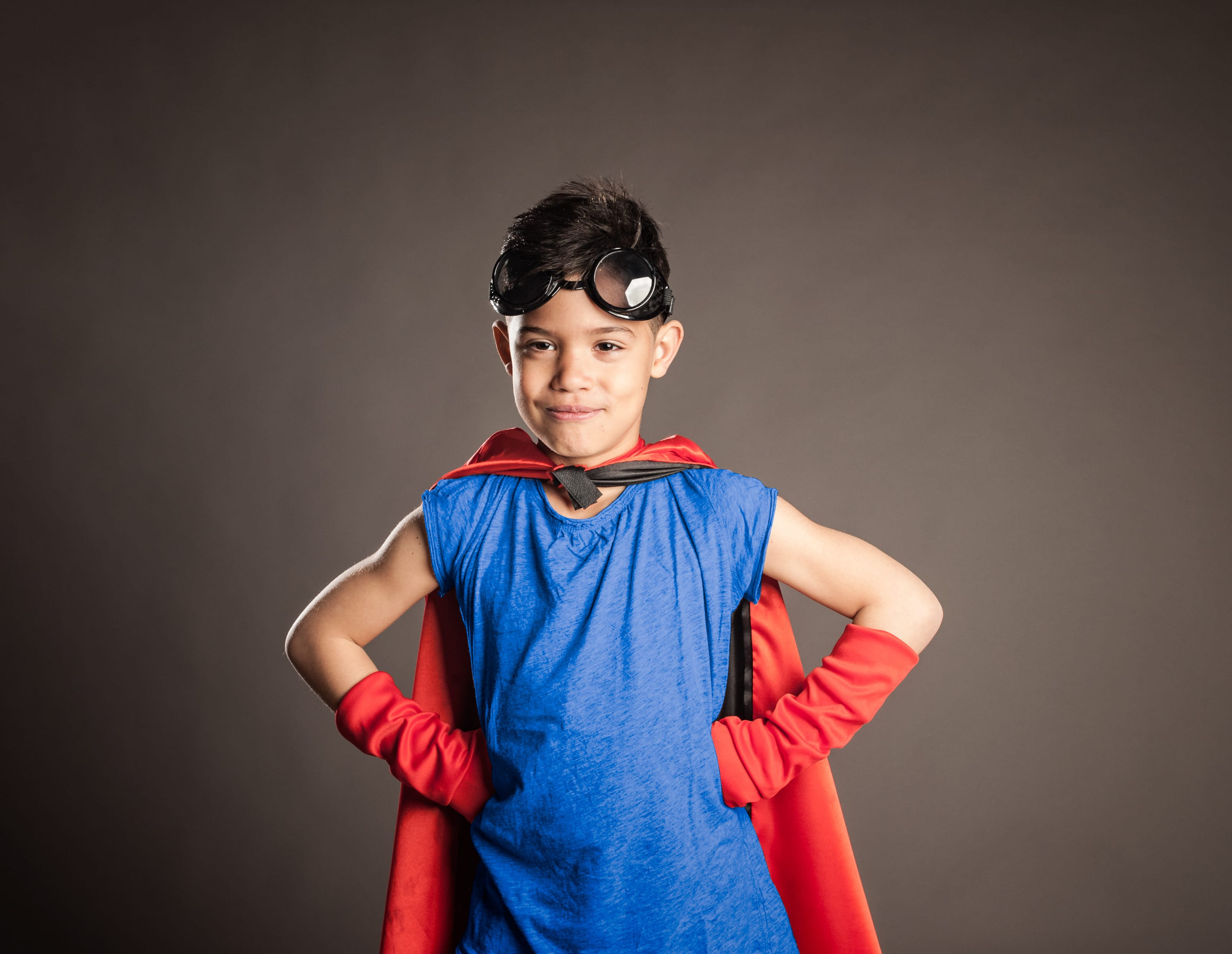 little boy wearing a superhero costume on a gray background