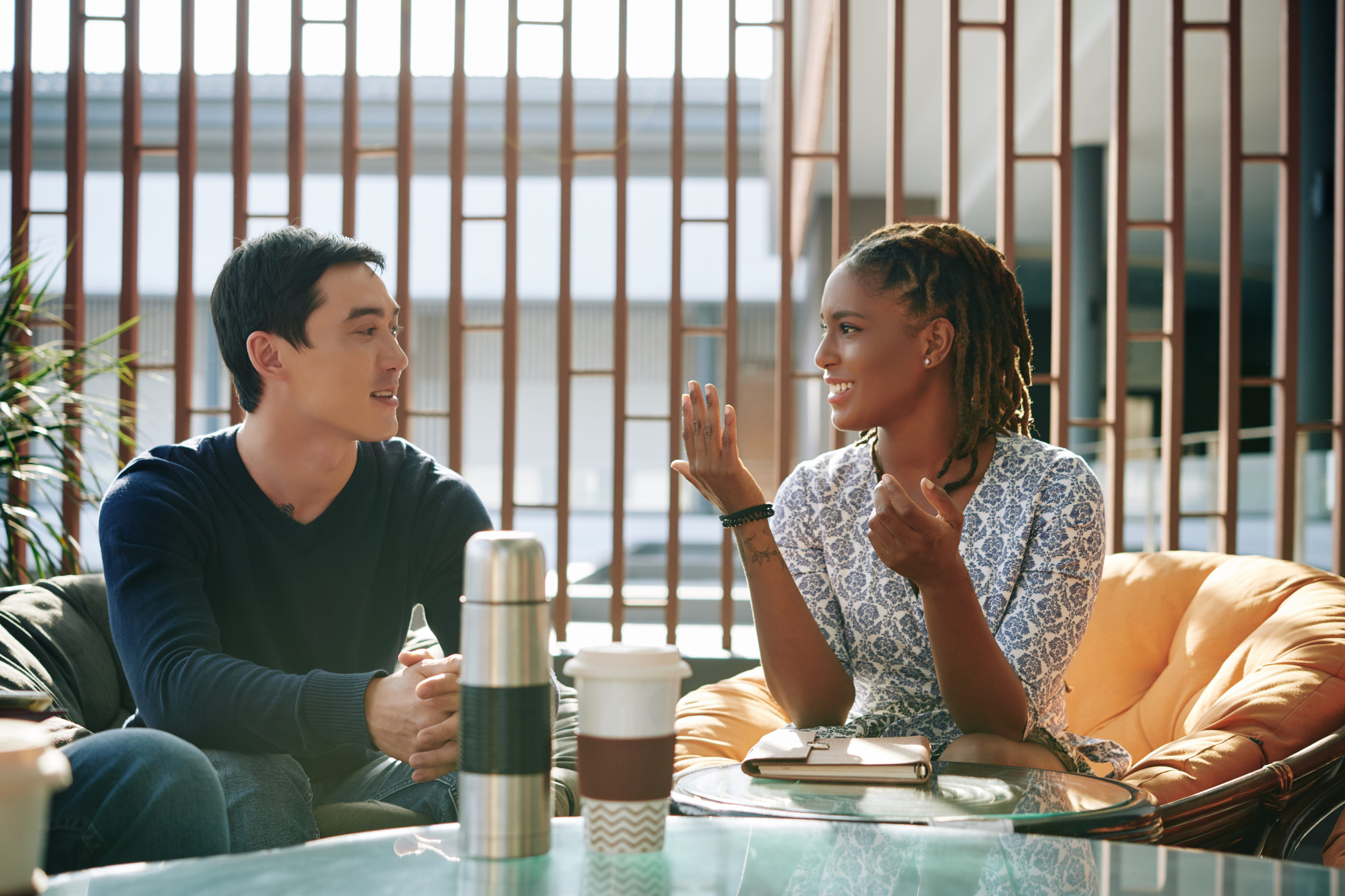 Positive emotional young businesswoman discussing news and ideas with colleague at meeting