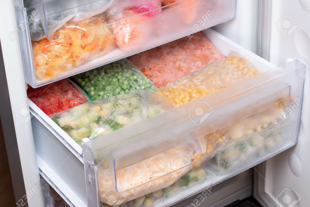 Plastic bags with different frozen vegetables in refrigerator. Food storage