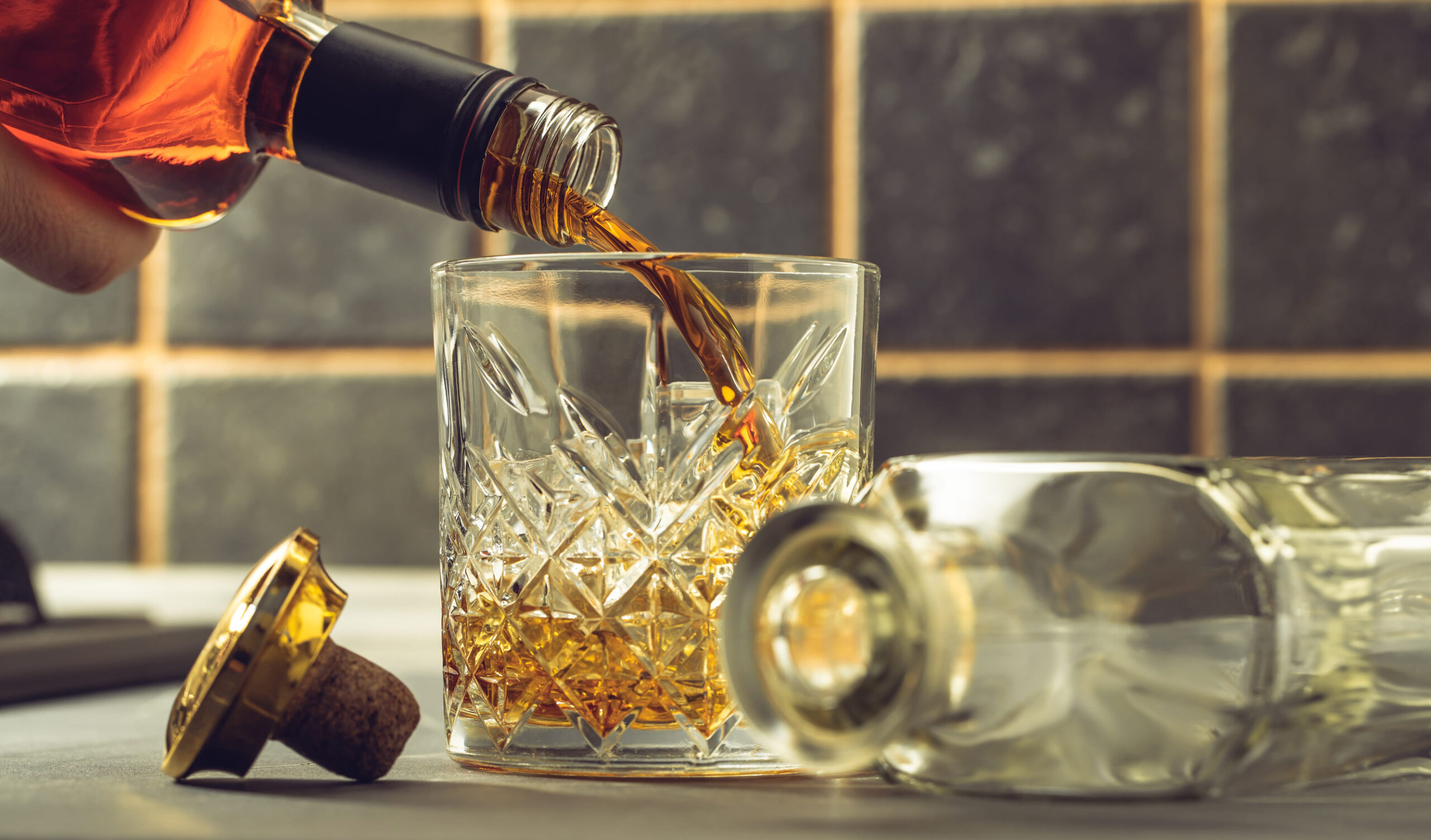 whiskey is poured into a glass from bottle