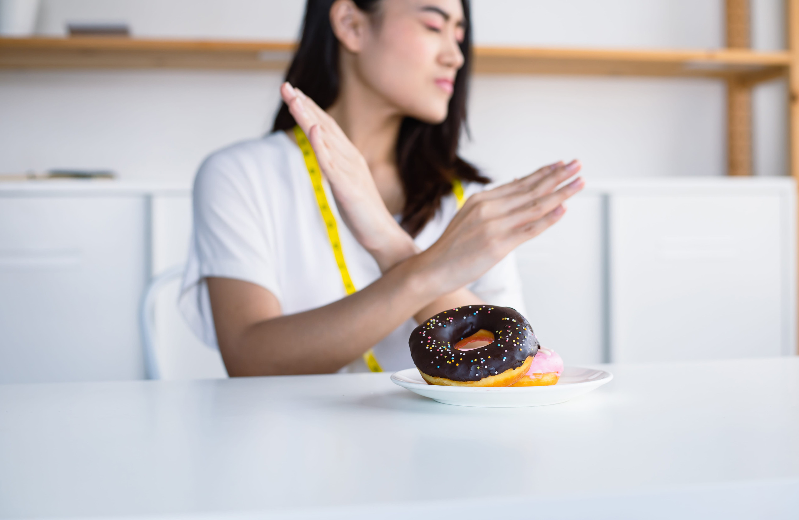 Asian women are reluctant to eat delicious donuts. Because her are aiming to lose weight.