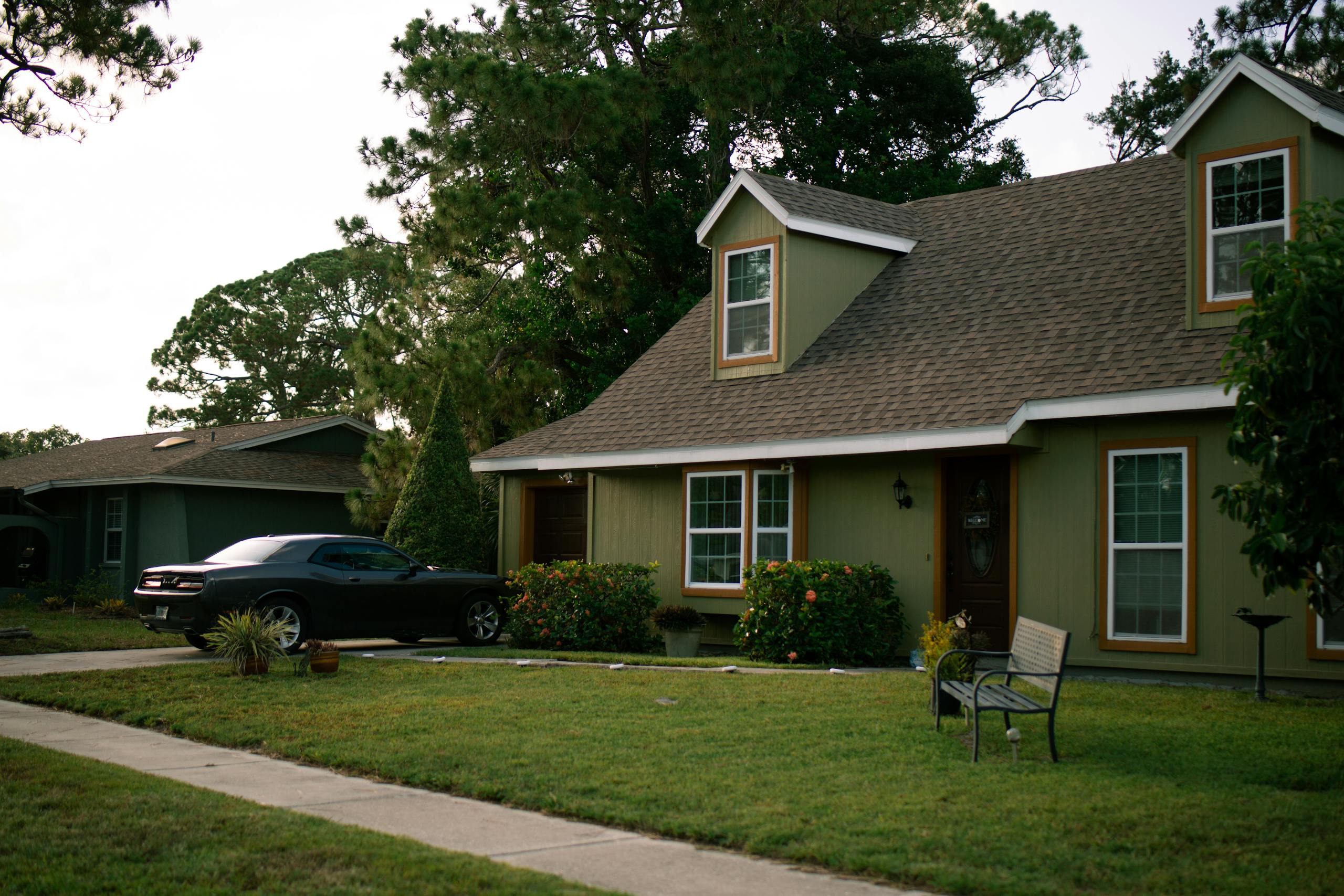 A beautiful suburban home with a well-maintained green lawn and parked car, highlighting residential comfort.