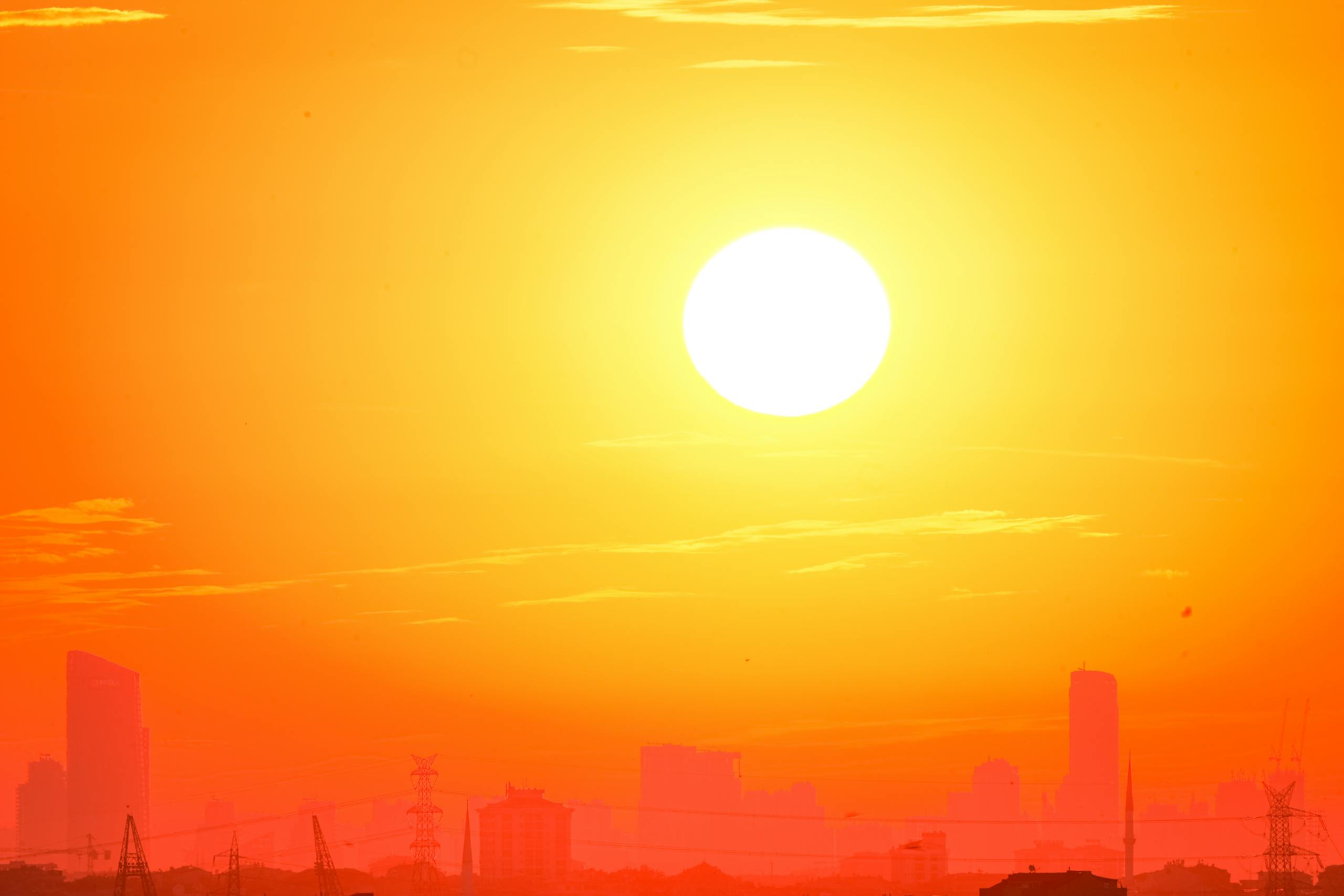 A city skyline silhouetted against a vivid, orange sunset sky.