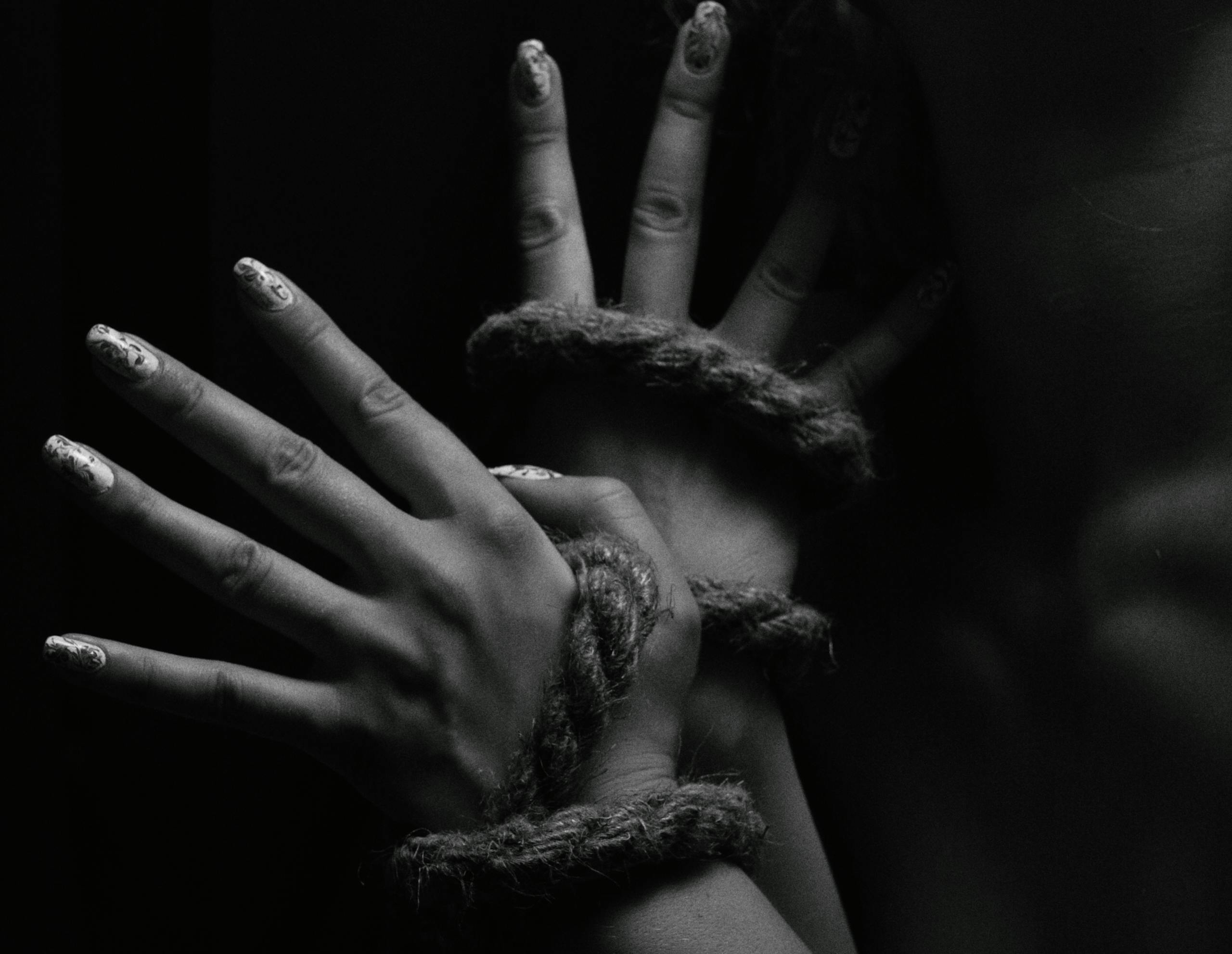 A close-up black and white photo depicting hands creatively bound with rope.
