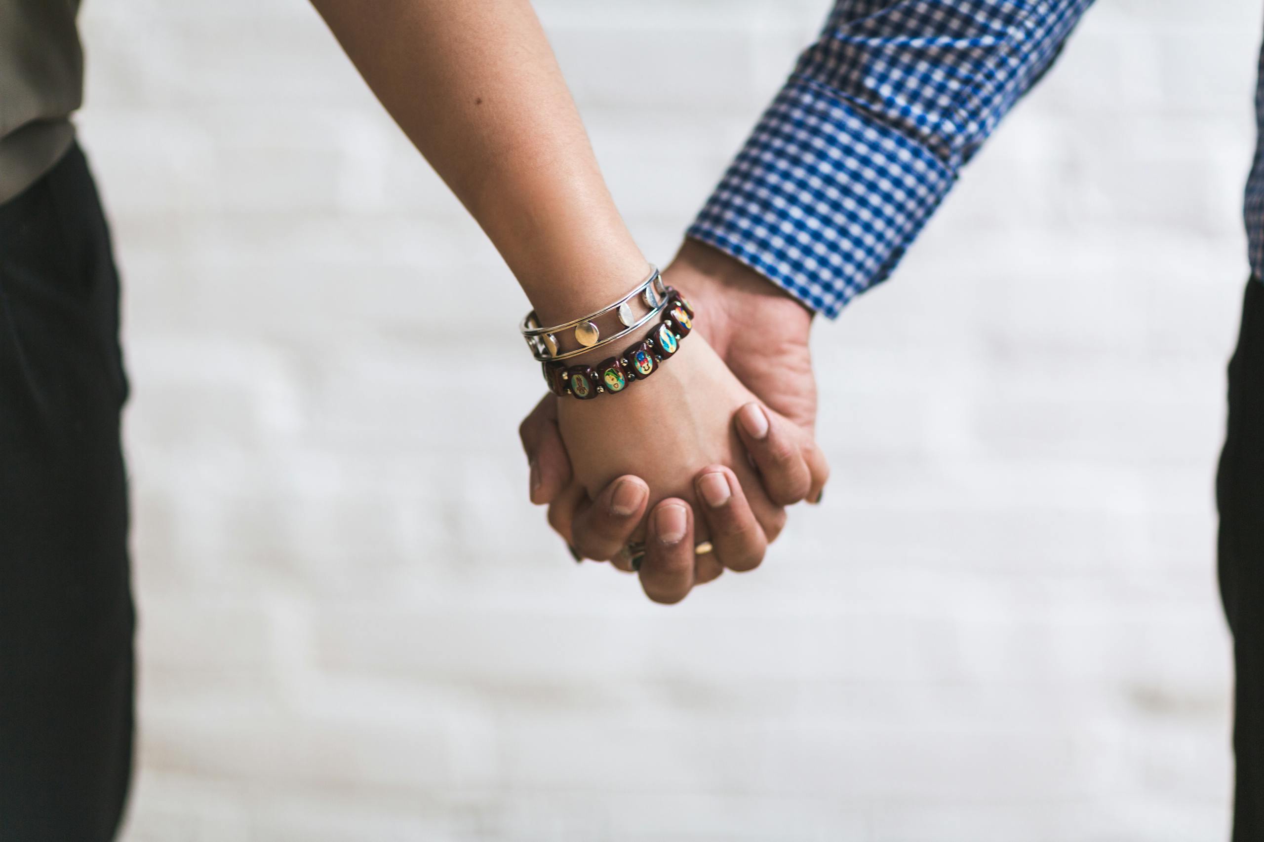 A close-up image of a couple holding hands outdoors symbolizing togetherness and unity.