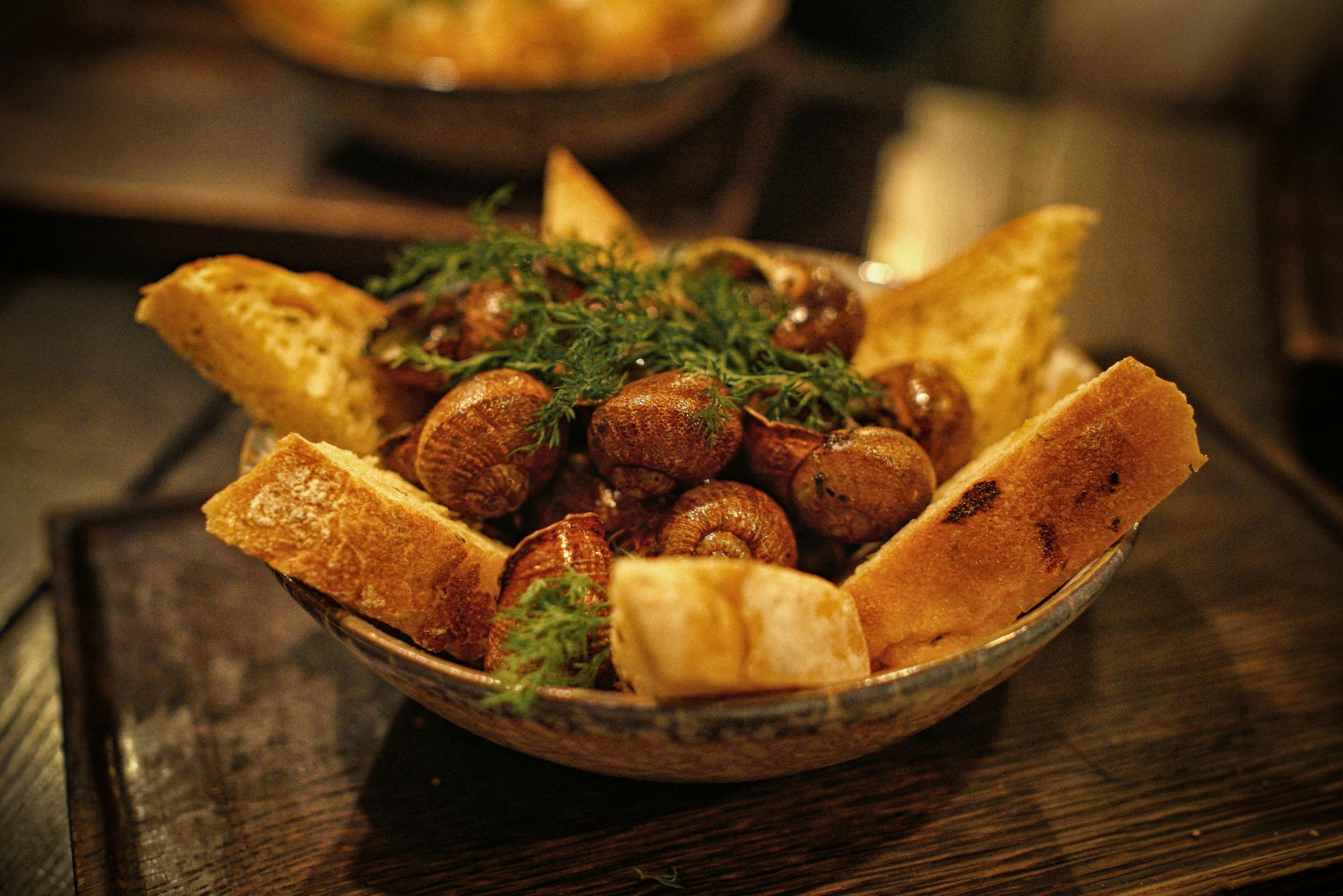 A close-up of a gourmet escargot dish with fresh herbs and crusty bread, perfect for food enthusiasts.