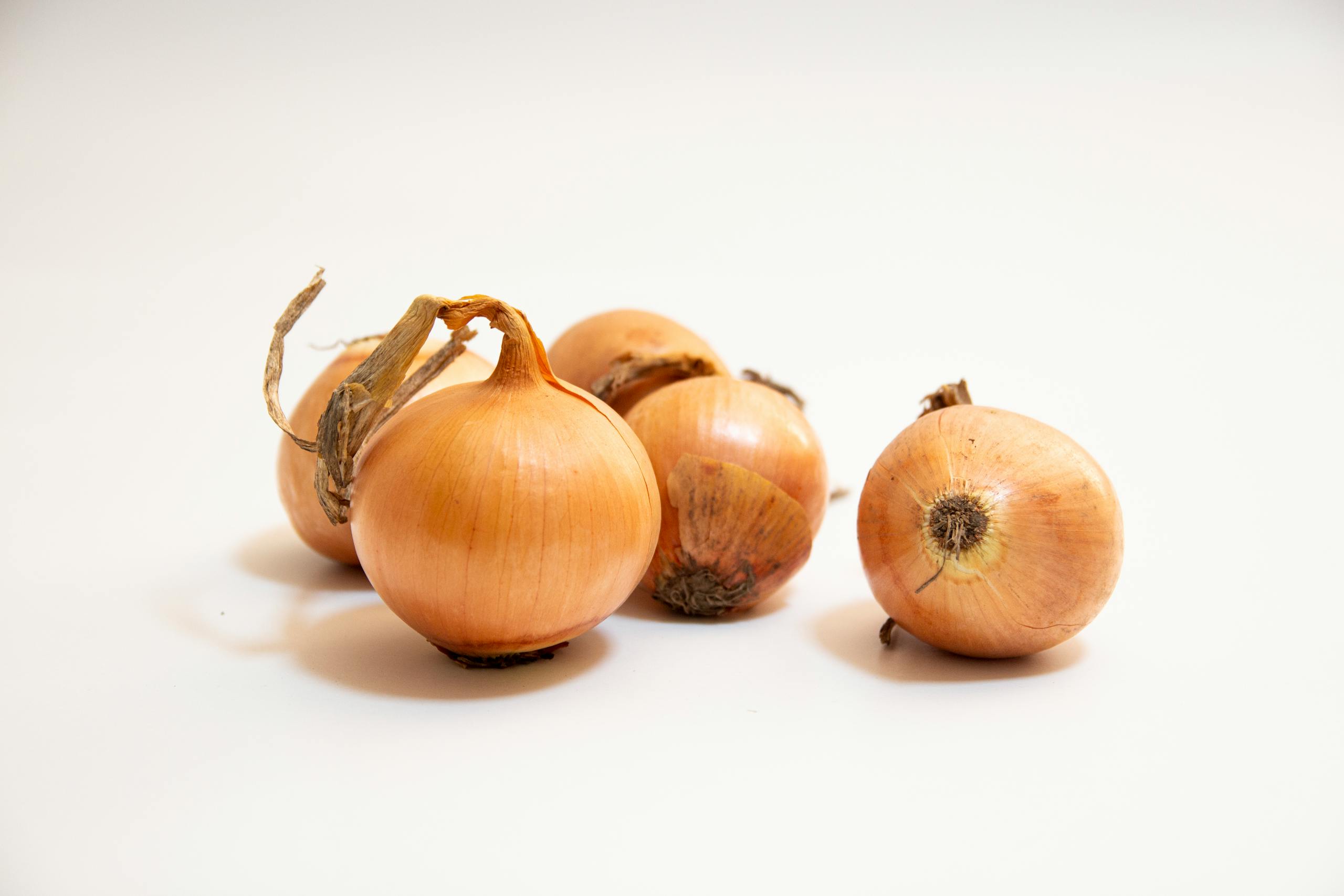A close-up of fresh brown onions on a white background, perfect for culinary concepts.