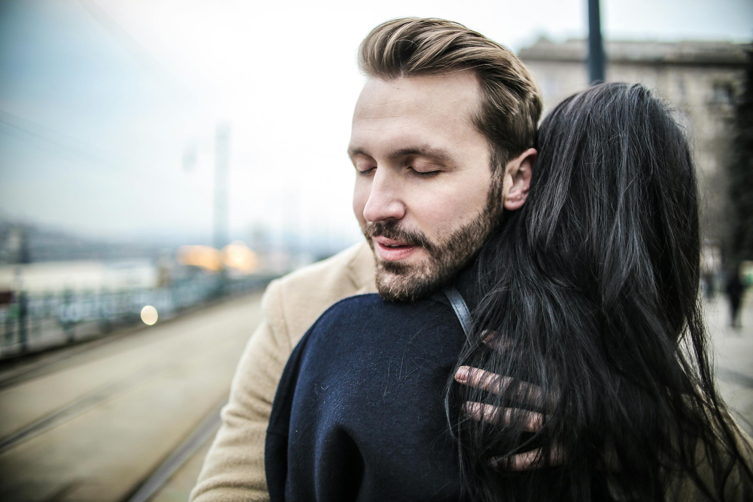 A closeup of a couple hugging warmly on a bustling city street, showcasing intimacy and affection.