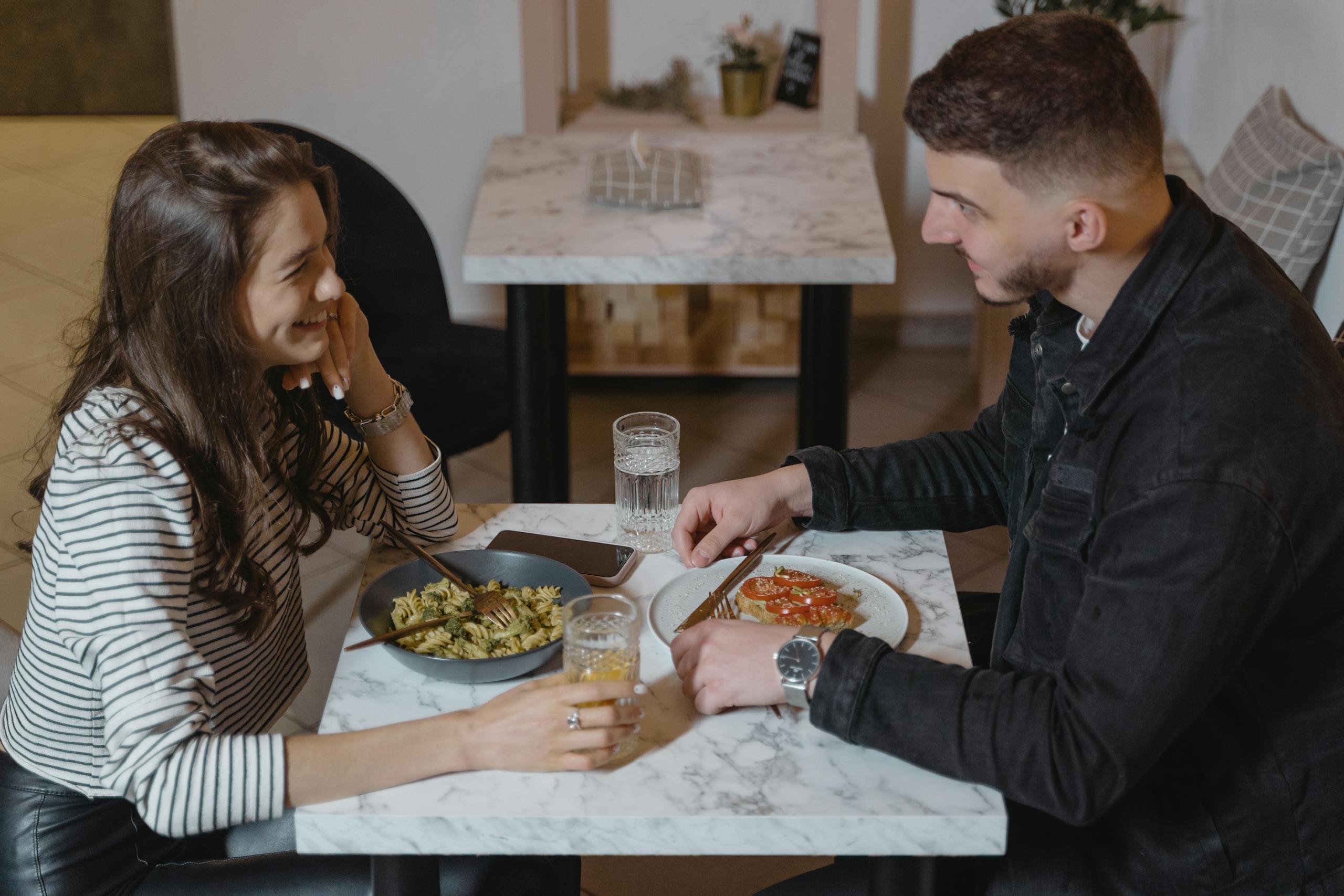 A couple dining at a modern restaurant table, enjoying a meal together indoors.