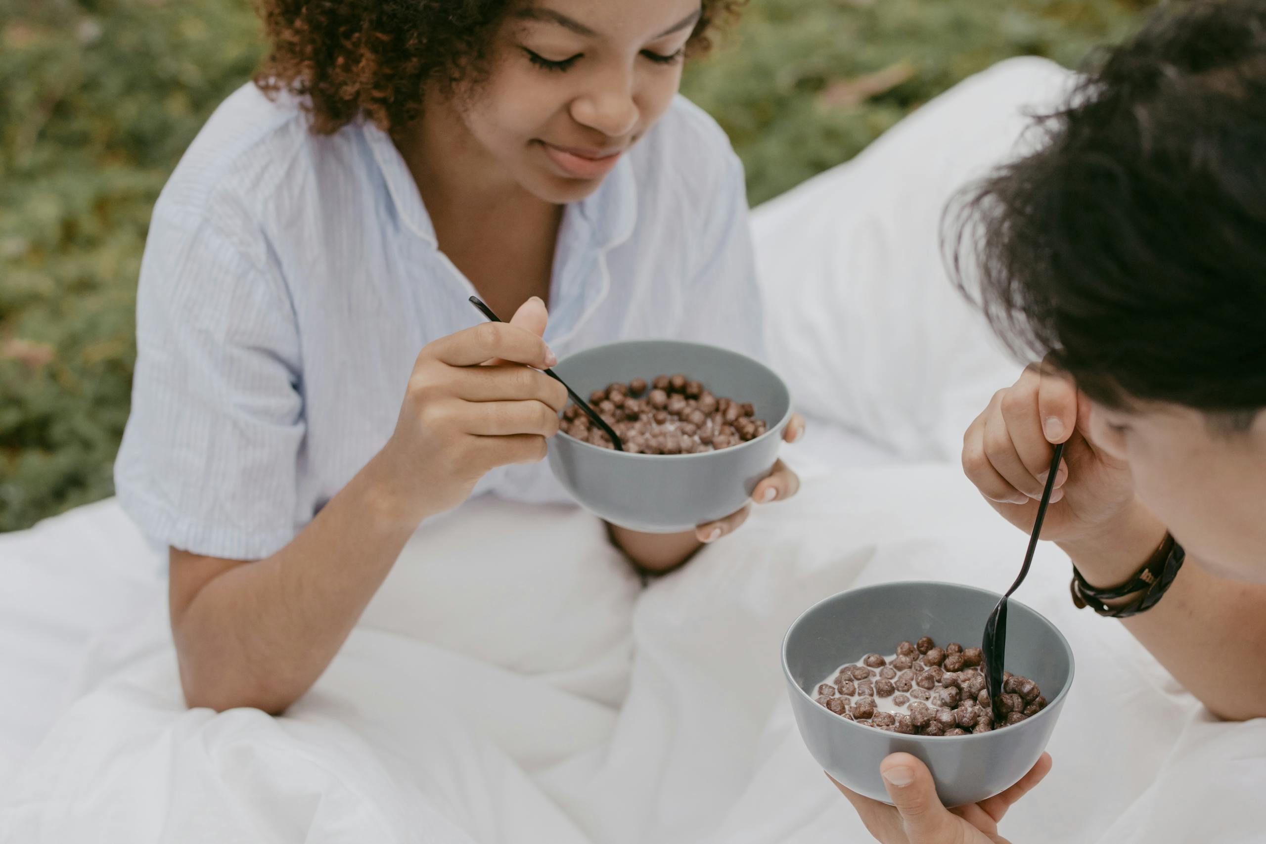 A couple enjoying a cozy outdoor breakfast with chocolate cereal.