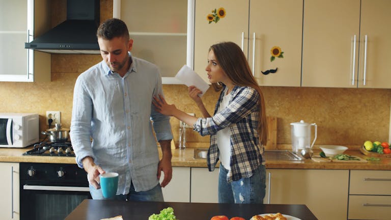 A couple having a disagreement in a modern kitchen setting, expressing emotional tension.