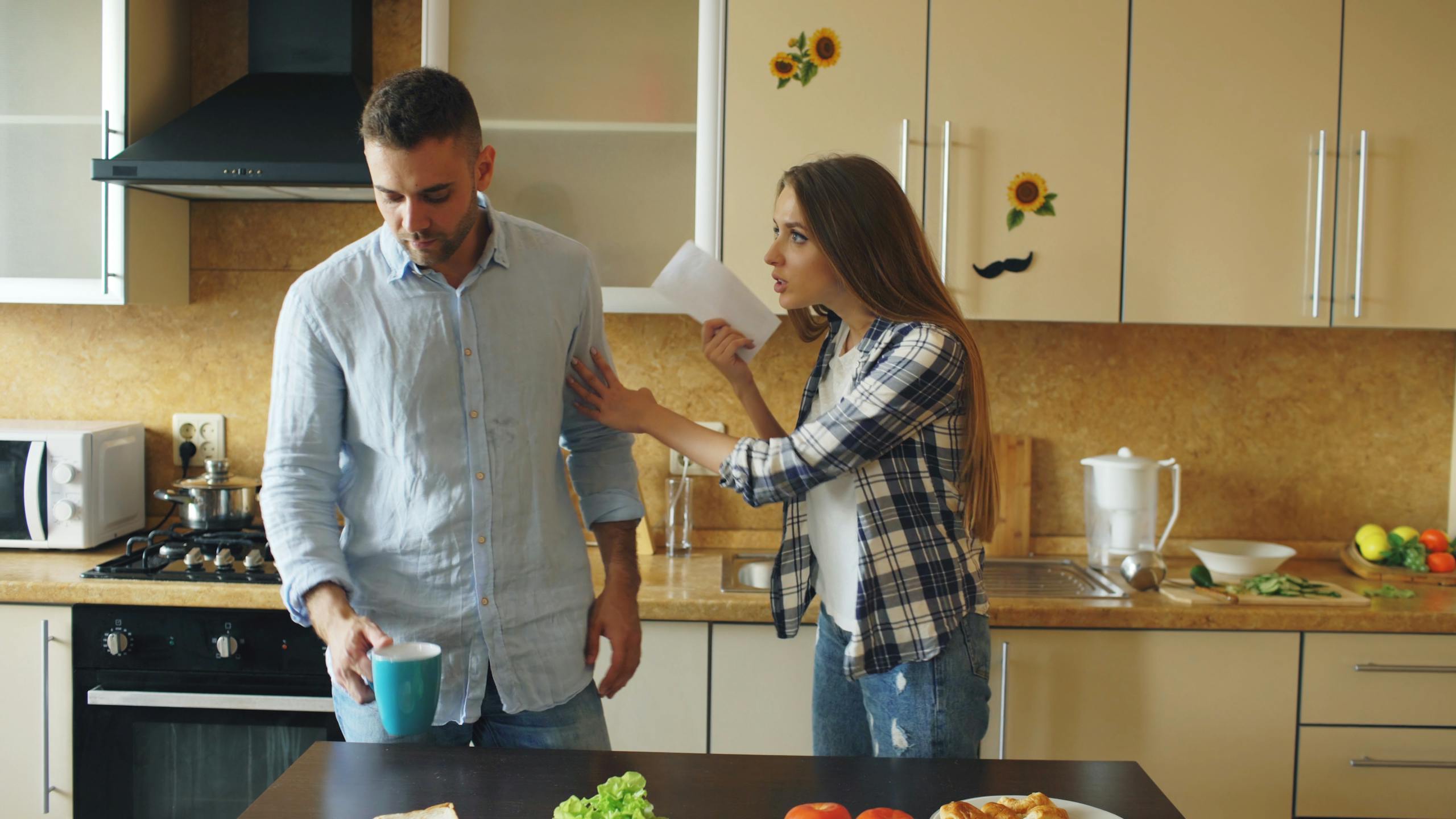 A couple having a disagreement in a modern kitchen setting, expressing emotional tension.