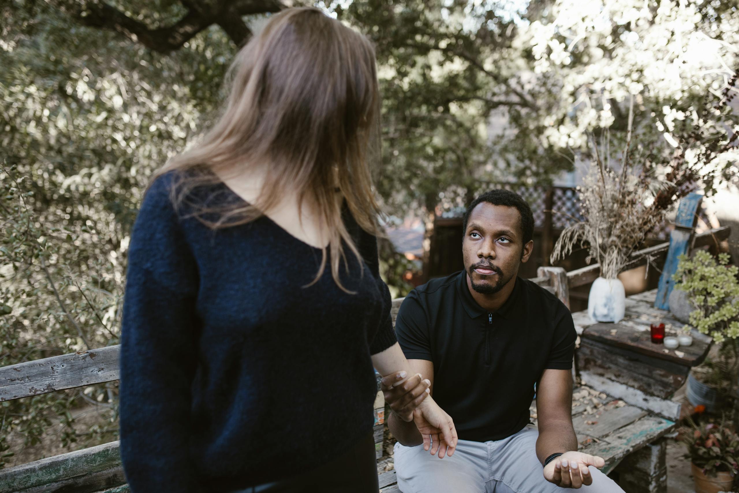 A couple in a serious discussion outdoors, surrounded by nature.