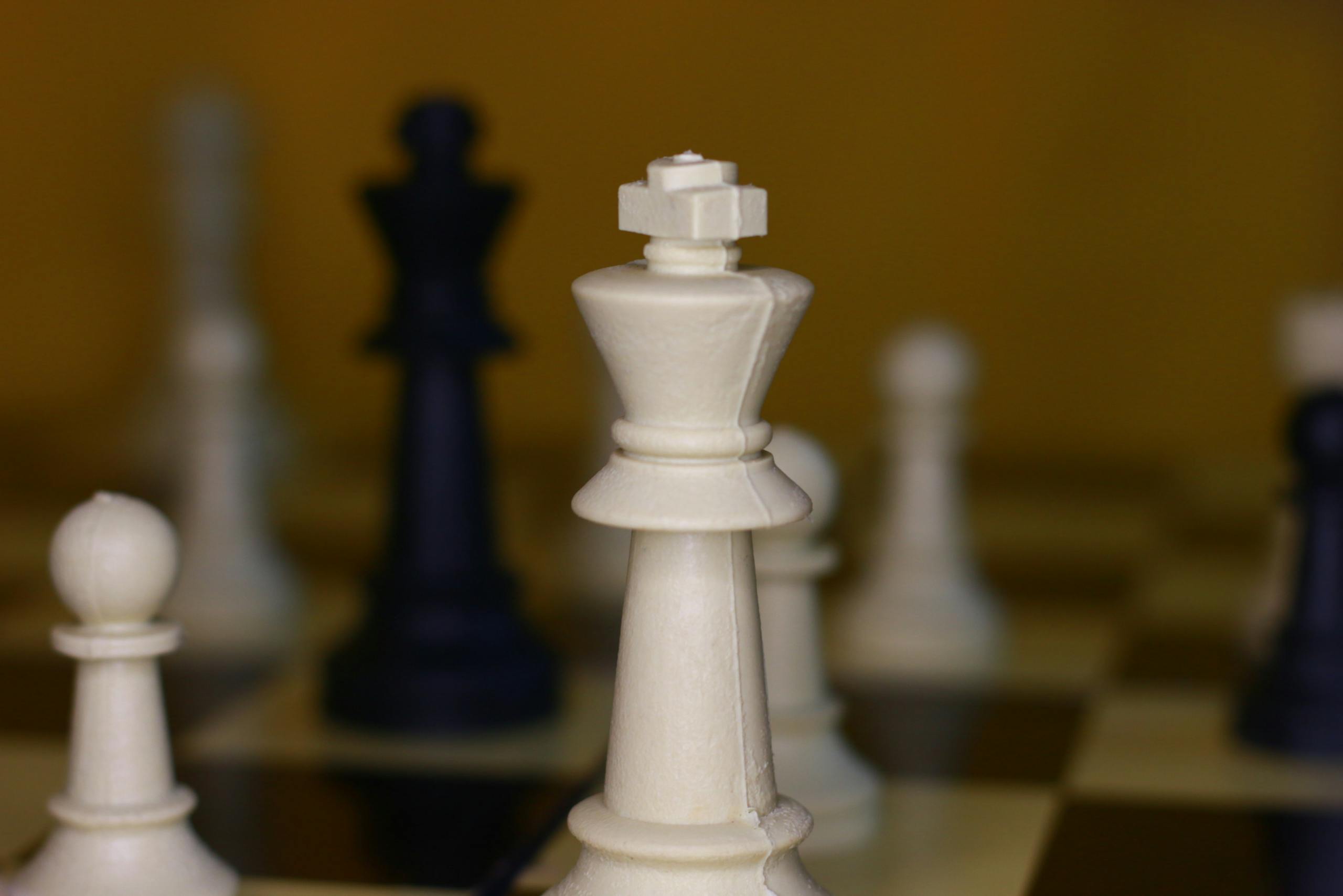 A detailed view of chess pieces, focusing on the white king during a strategic game.