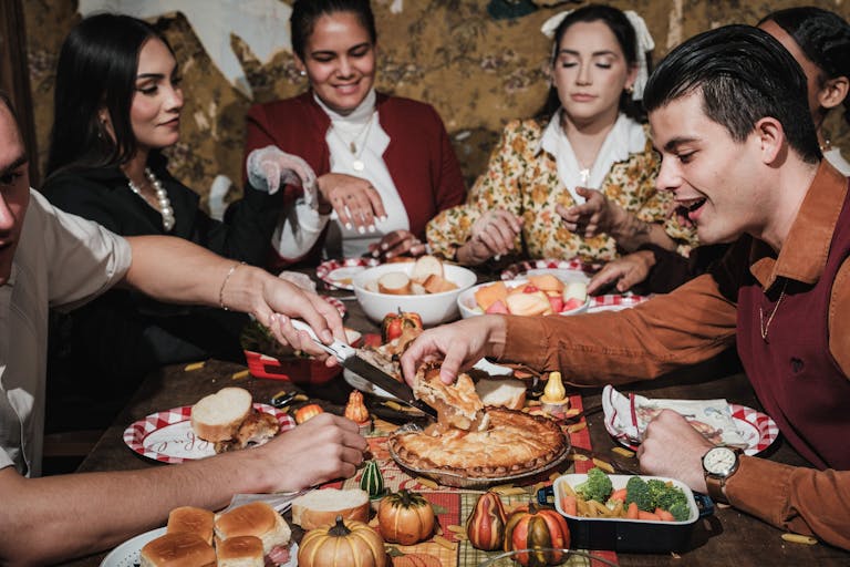 A diverse group enjoys a festive Thanksgiving meal with pie and decorations.