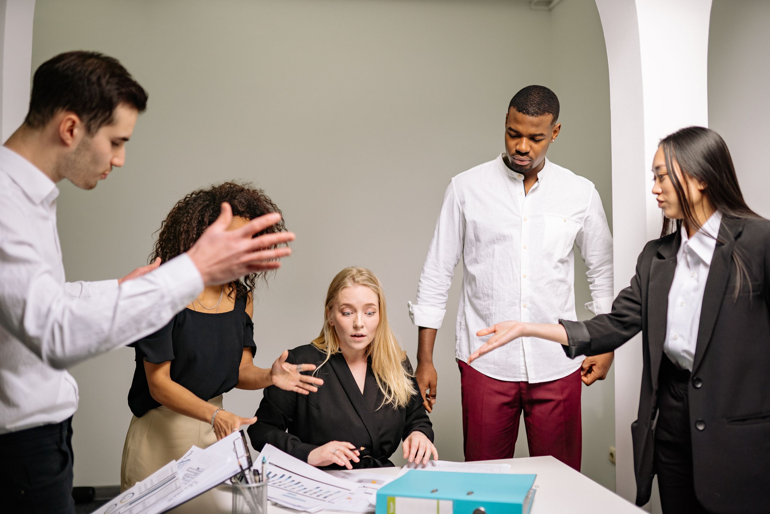A diverse group of colleagues engaged in an intense discussion in an office setting.