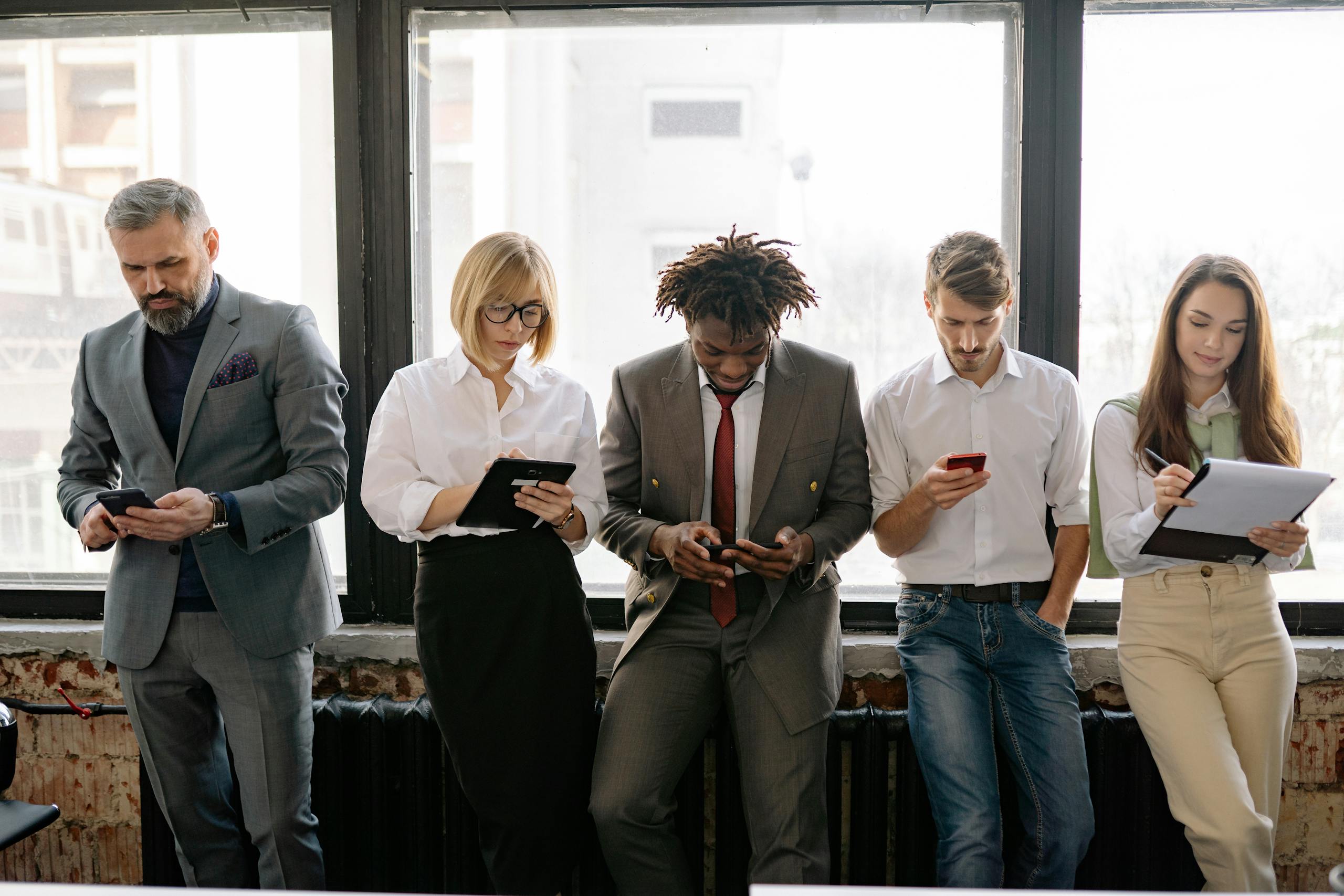 A diverse group of colleagues using mobile devices in an office setting.
