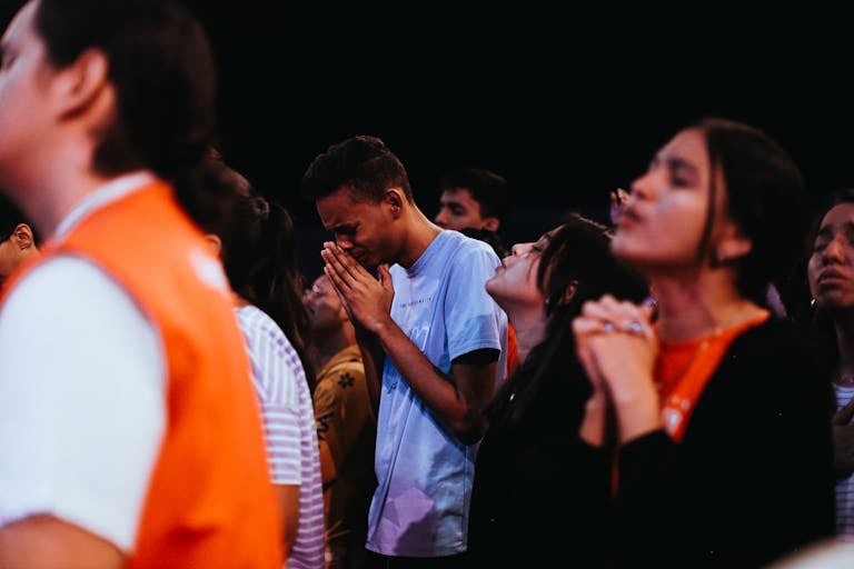 A diverse group of young people praying passionately at a religious gathering.