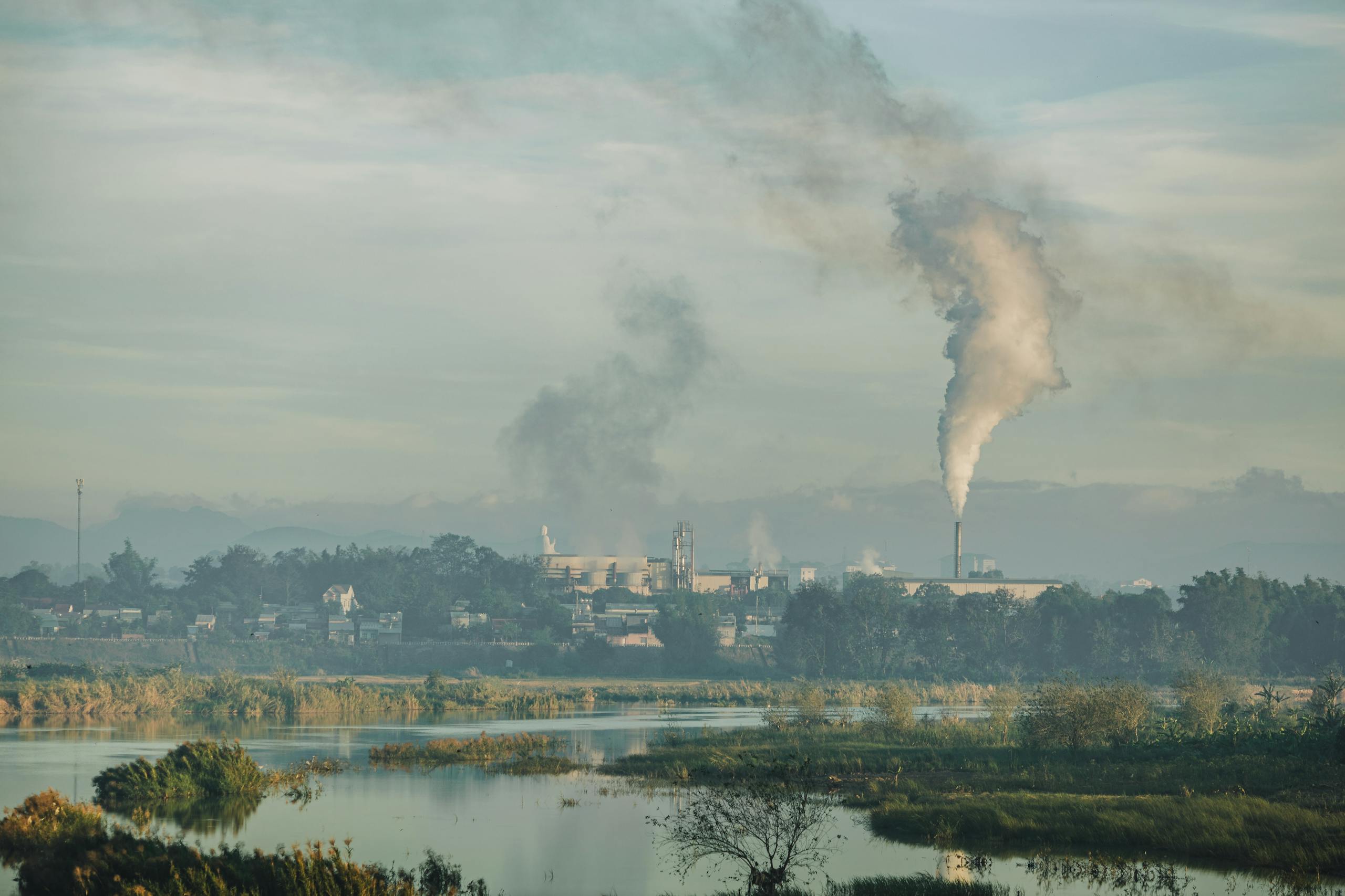 A factory emitting smoke over a natural landscape in Kon Tum, Vietnam.