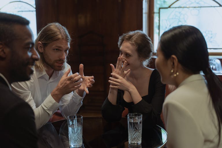 A group of friends talking and laughing around a table in a cozy indoor setting.