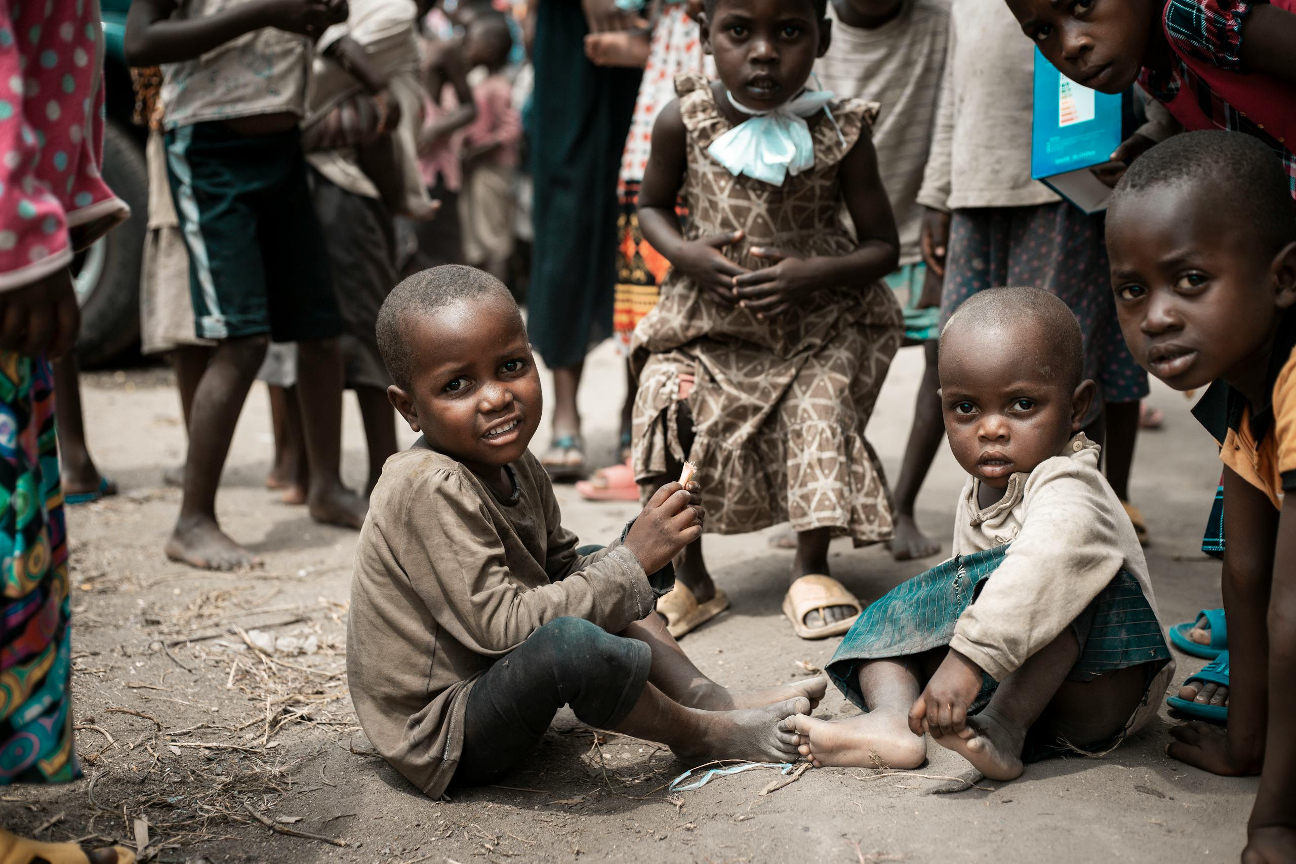 A group of smiling children sitting outdoors, capturing a candid, playful moment in a community setting.
