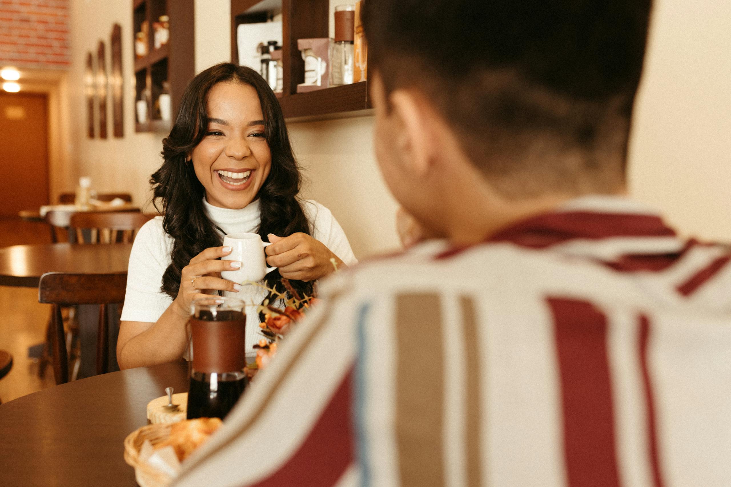 A happy couple enjoying a coffee date in a warm, cozy cafe setting.