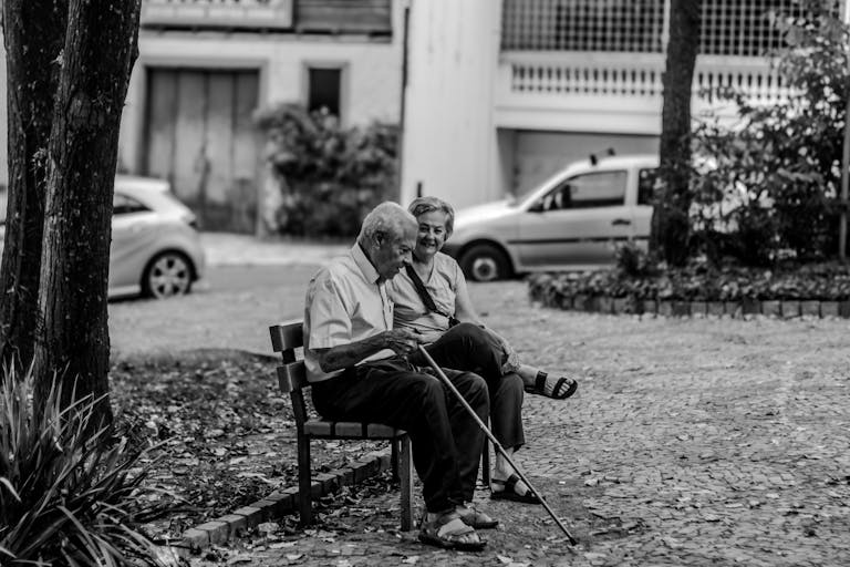 A happy senior couple sitting on a bench, enjoying the outdoors in black and white.