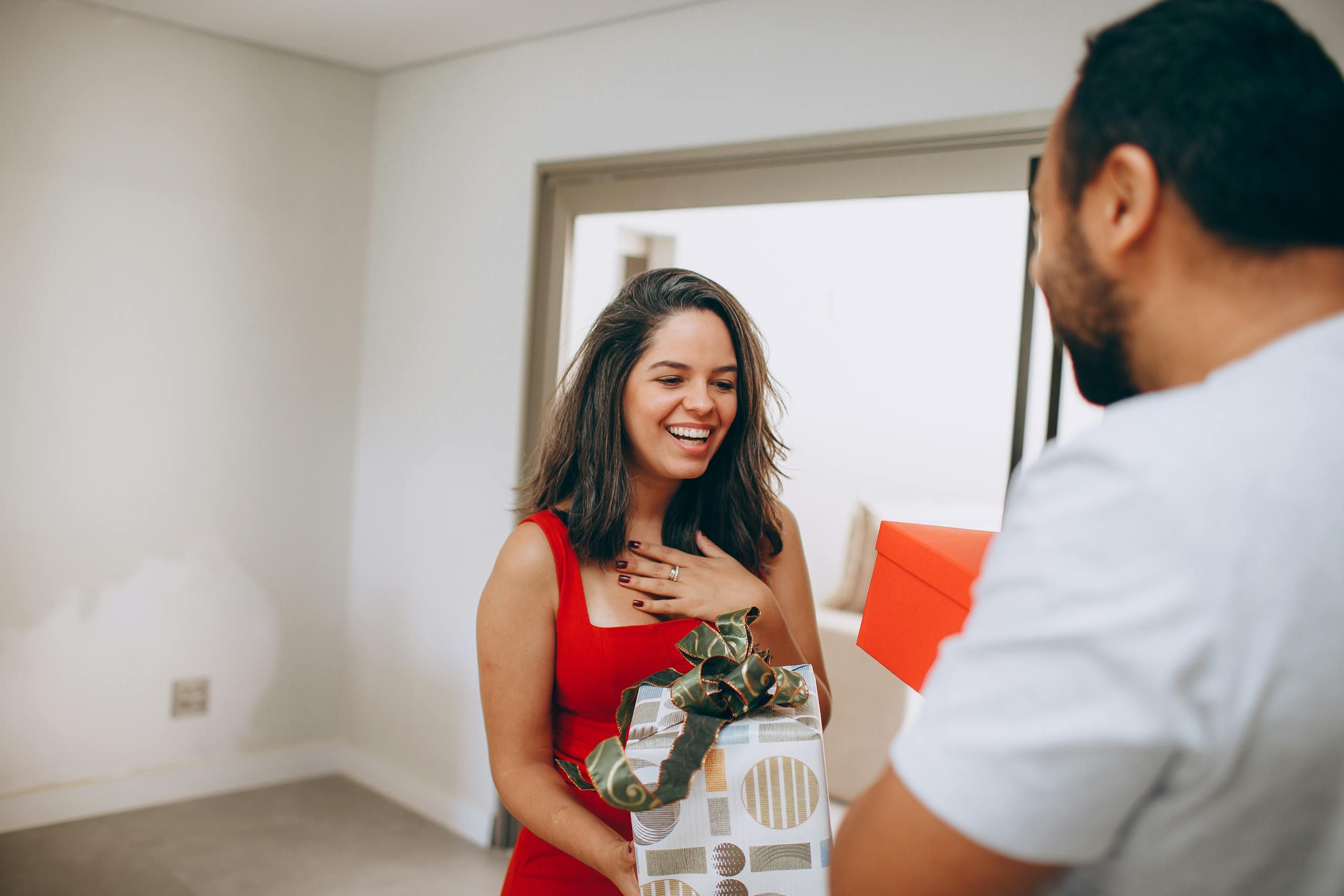A happy woman receiving a gift from a man, capturing a moment of joy and affection.