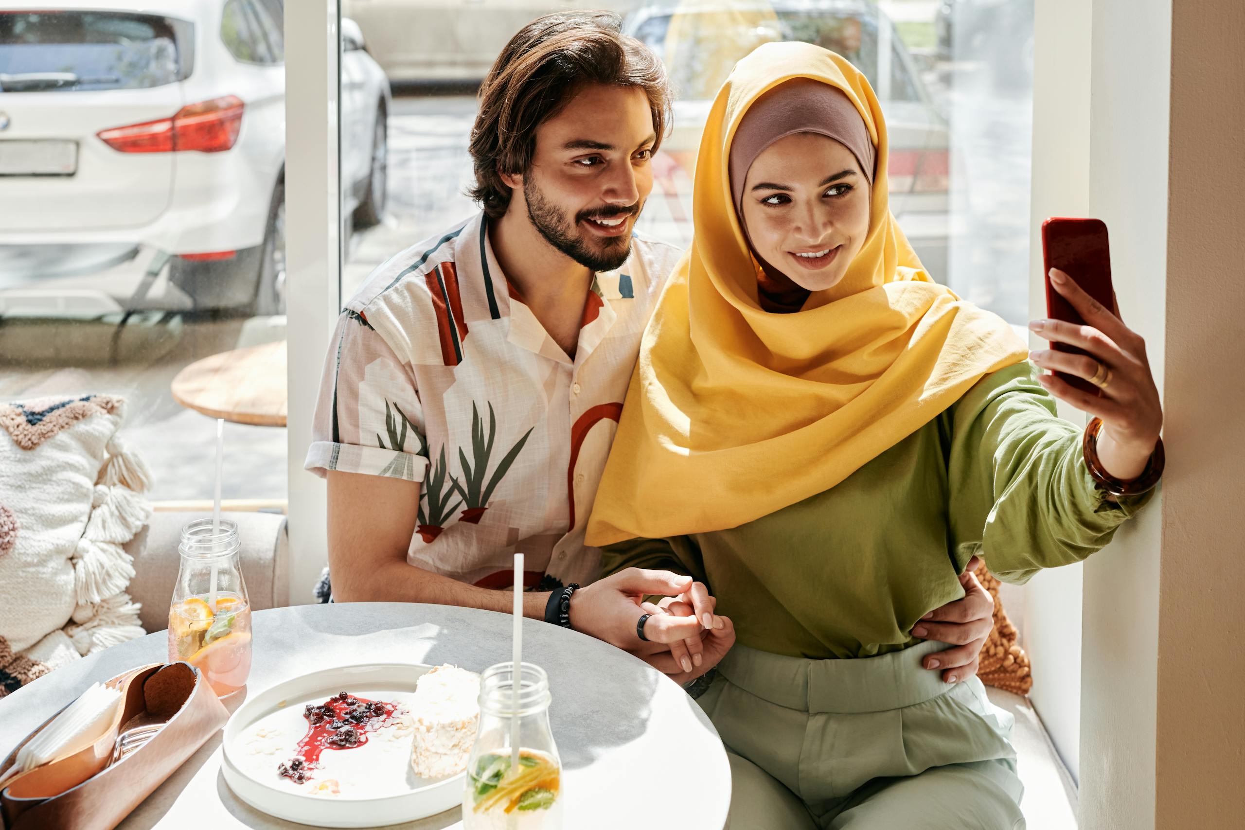 A joyful couple enjoying their time in a cafe, capturing a selfie.