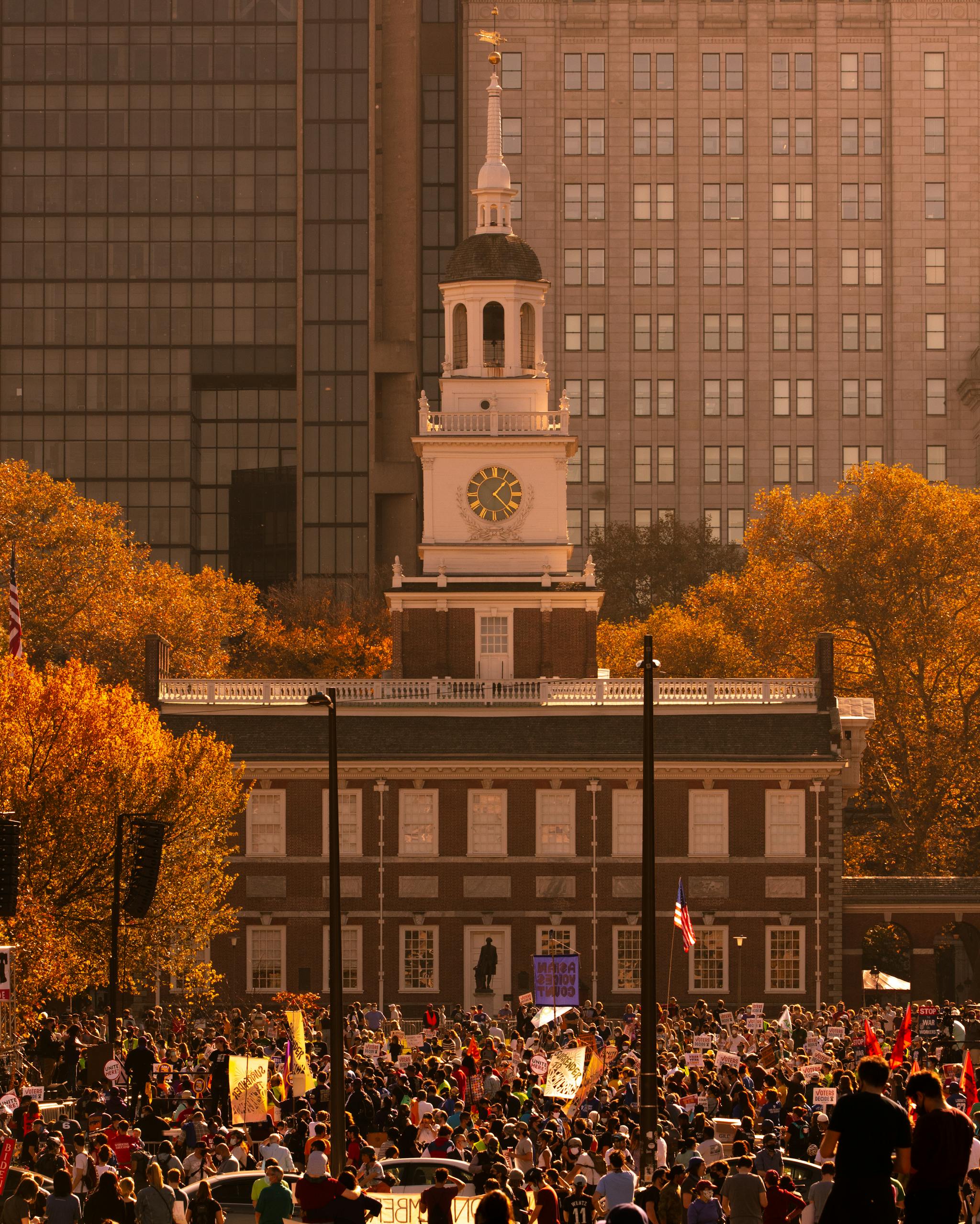 A large protest gathers outside the historic Independence Hall in Philadelphia during autumn.