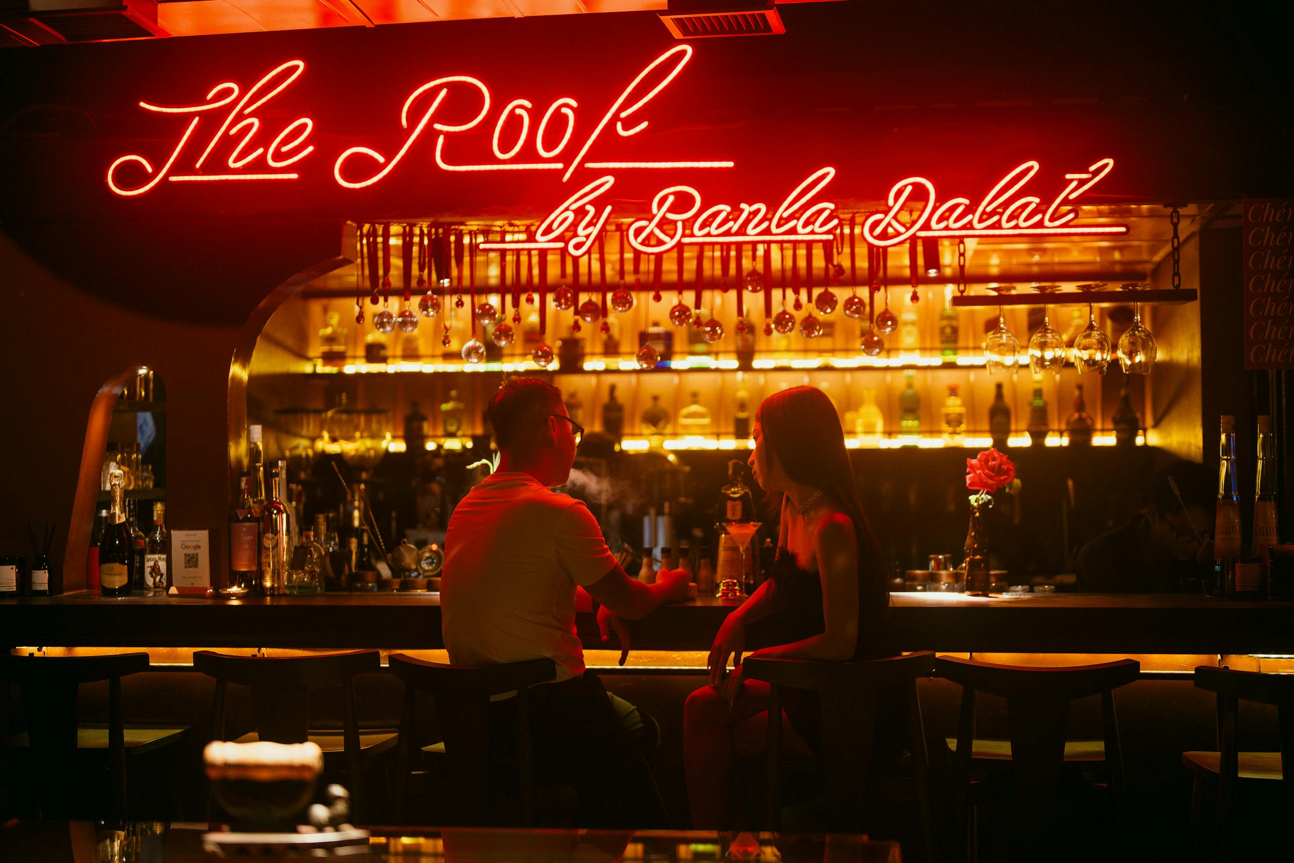 A lively evening atmosphere at The Roof with people enjoying drinks at the bar.