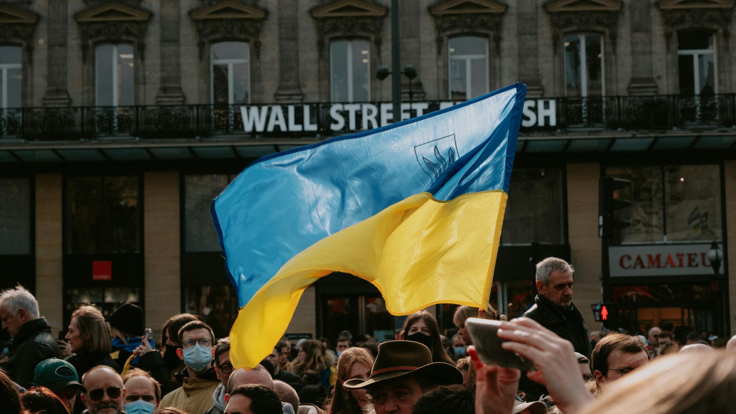 A lively protest with a prominent Ukrainian flag in an urban street setting.