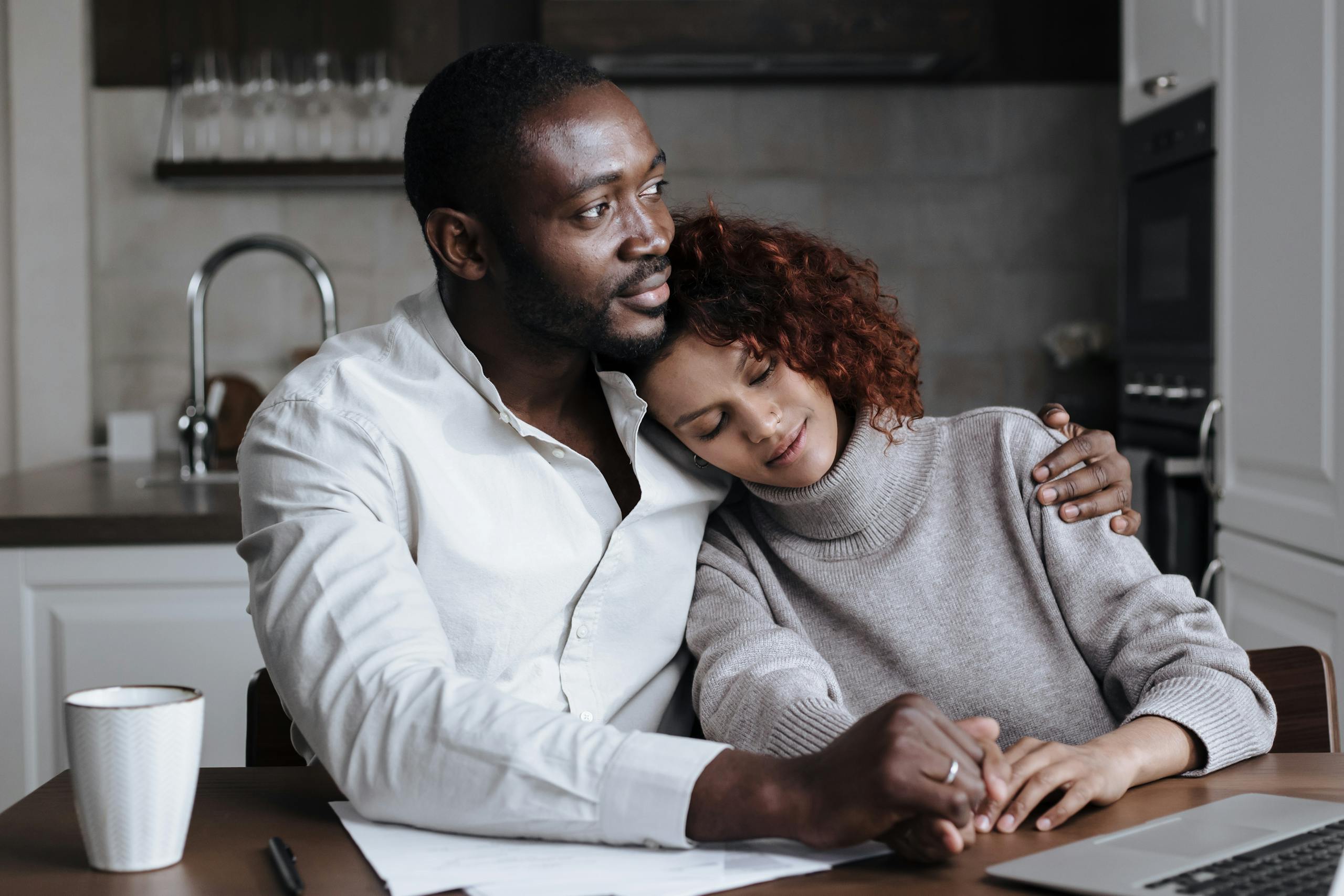 A loving couple embracing in a modern kitchen setting, sharing a peaceful moment together.