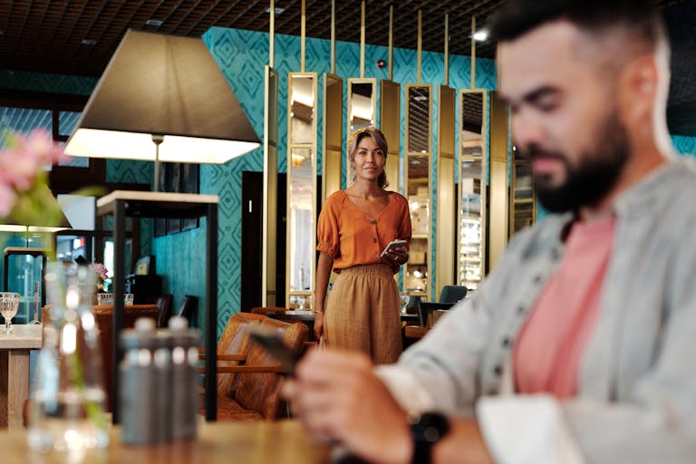 A man and woman at a modern restaurant setting, with warm interior decor.
