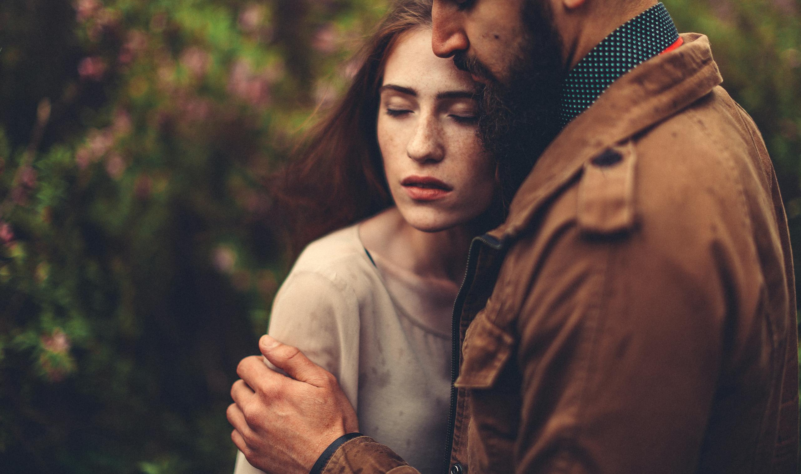 A man and woman embrace tenderly outdoors, conveying love and connection.