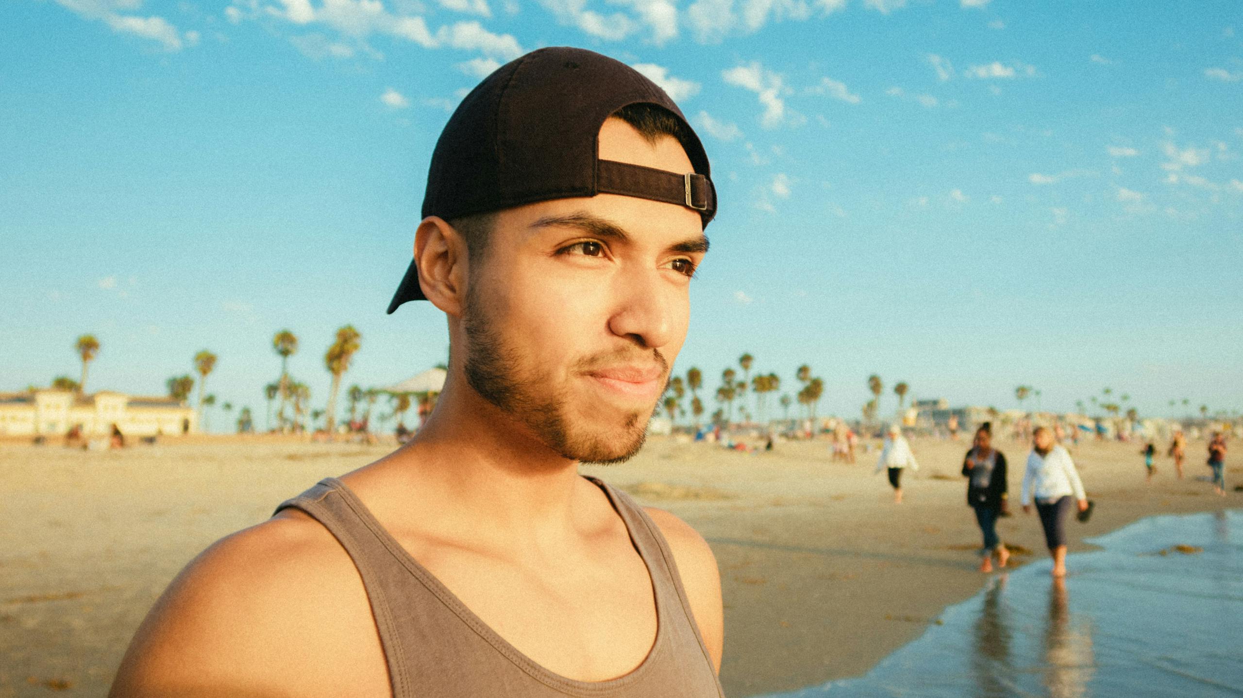 A man with a cap on a sunny beach day, perfect for summer leisure.