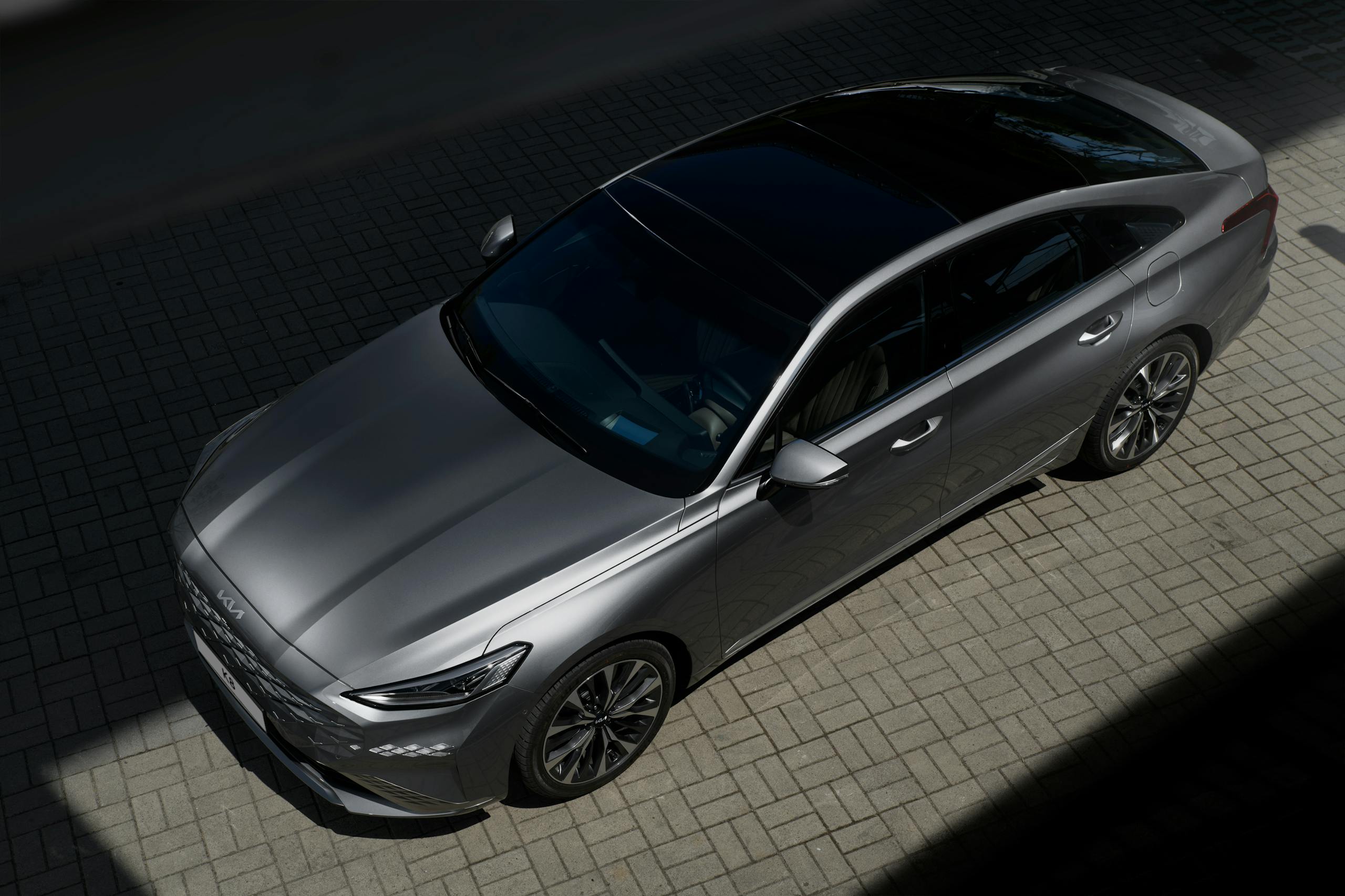 A modern silver sedan parked on a paved surface under sunlight, showcasing its sleek design.