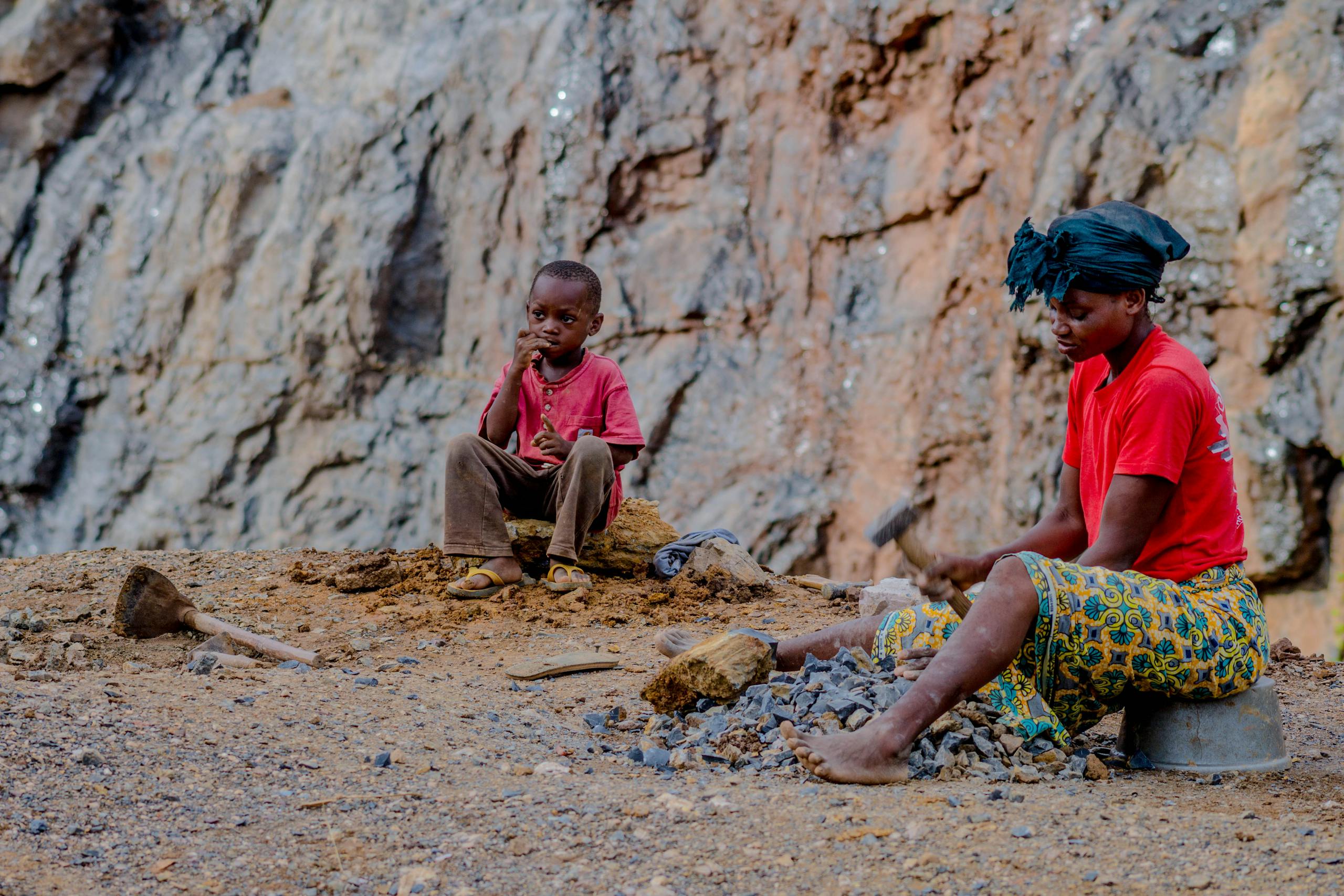 A mother and child in a rural setting mining stones together.