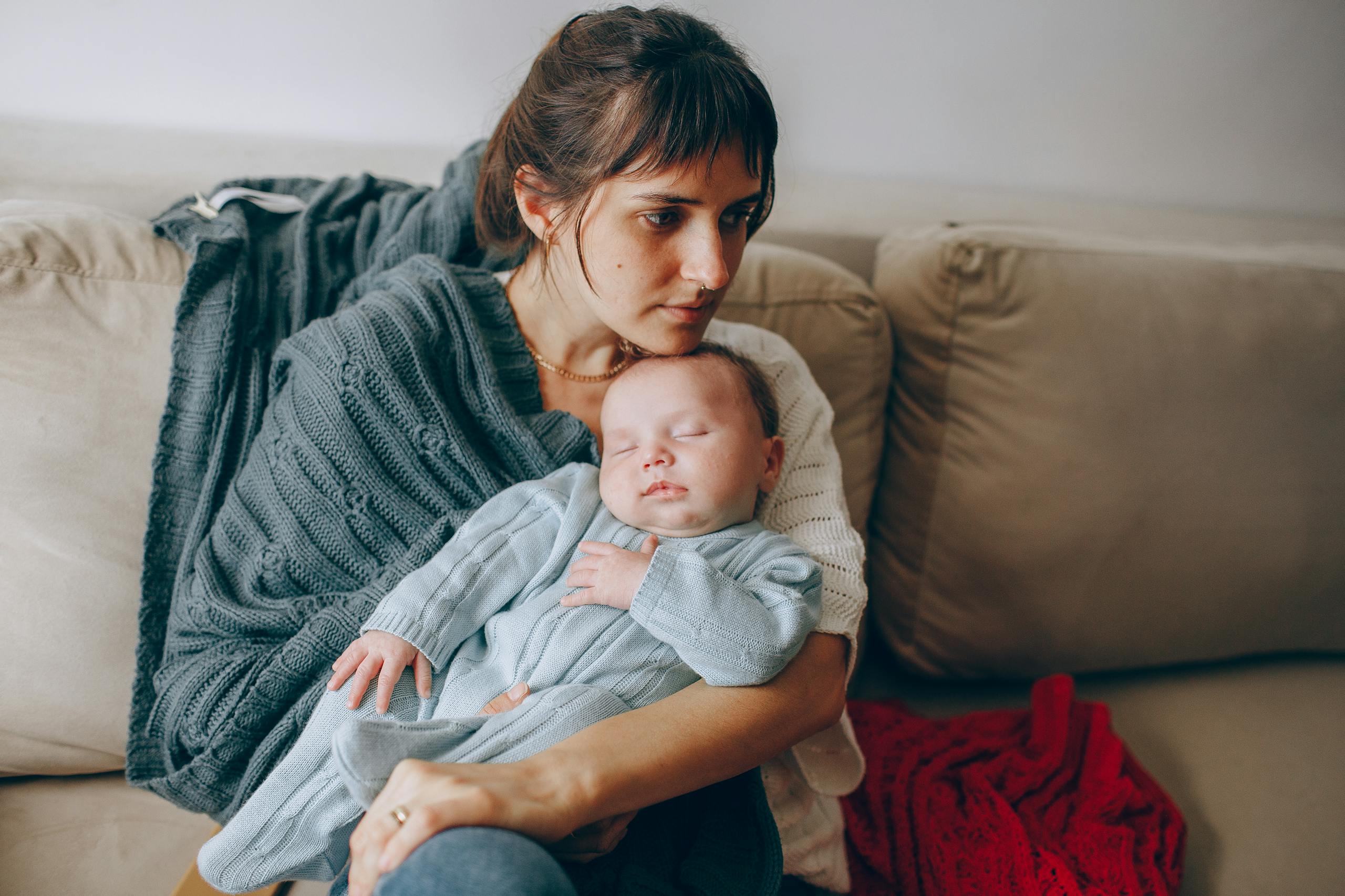 A peaceful moment as a mother holds her sleeping baby on a cozy couch.