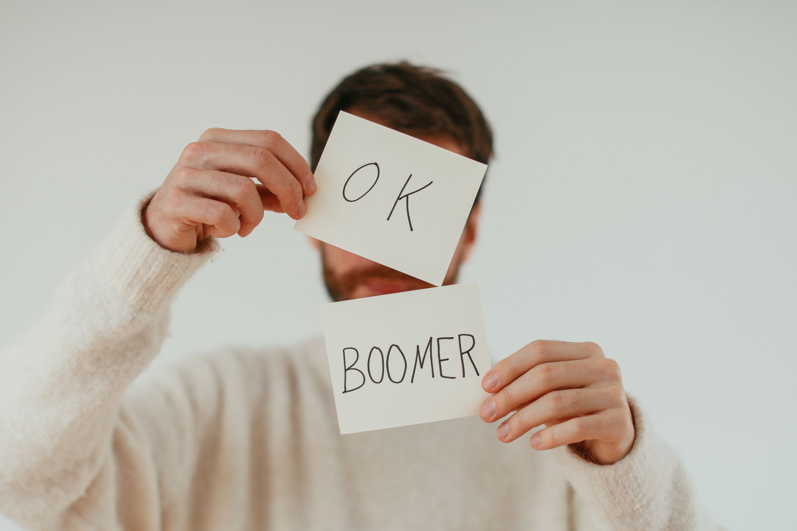 A person holding two cards with 'OK Boomer' written in bold text.