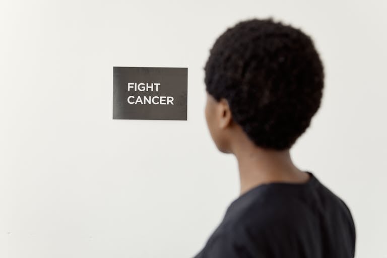A person looking at a 'Fight Cancer' sign symbolizes cancer awareness.