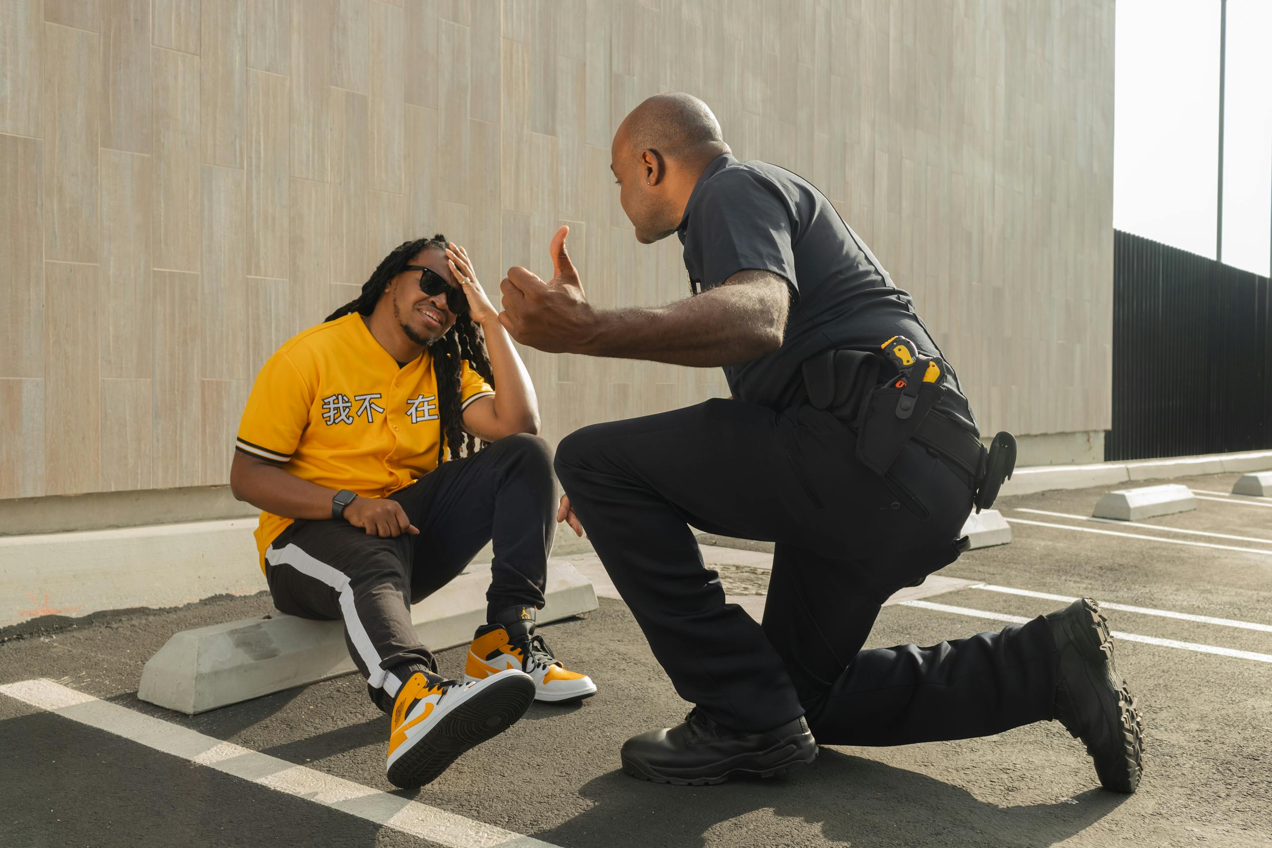 A police officer interacts with a man in a yellow shirt in a parking lot.