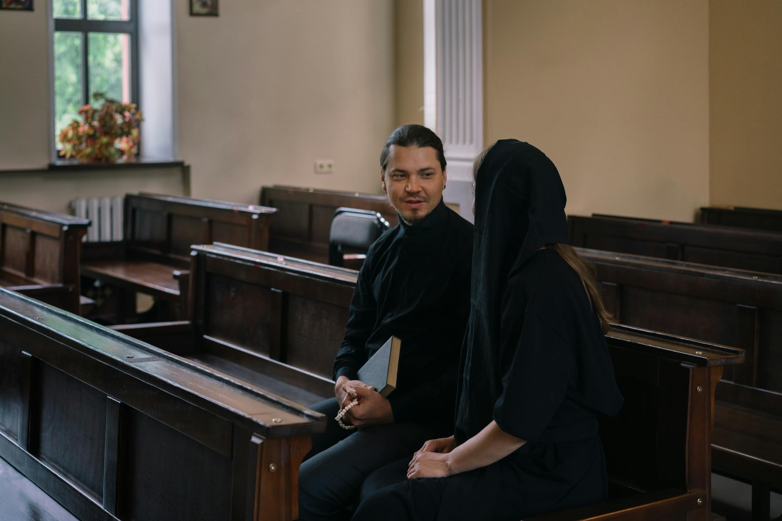 A priest and woman engaged in conversation inside a church, highlighting religious connection.