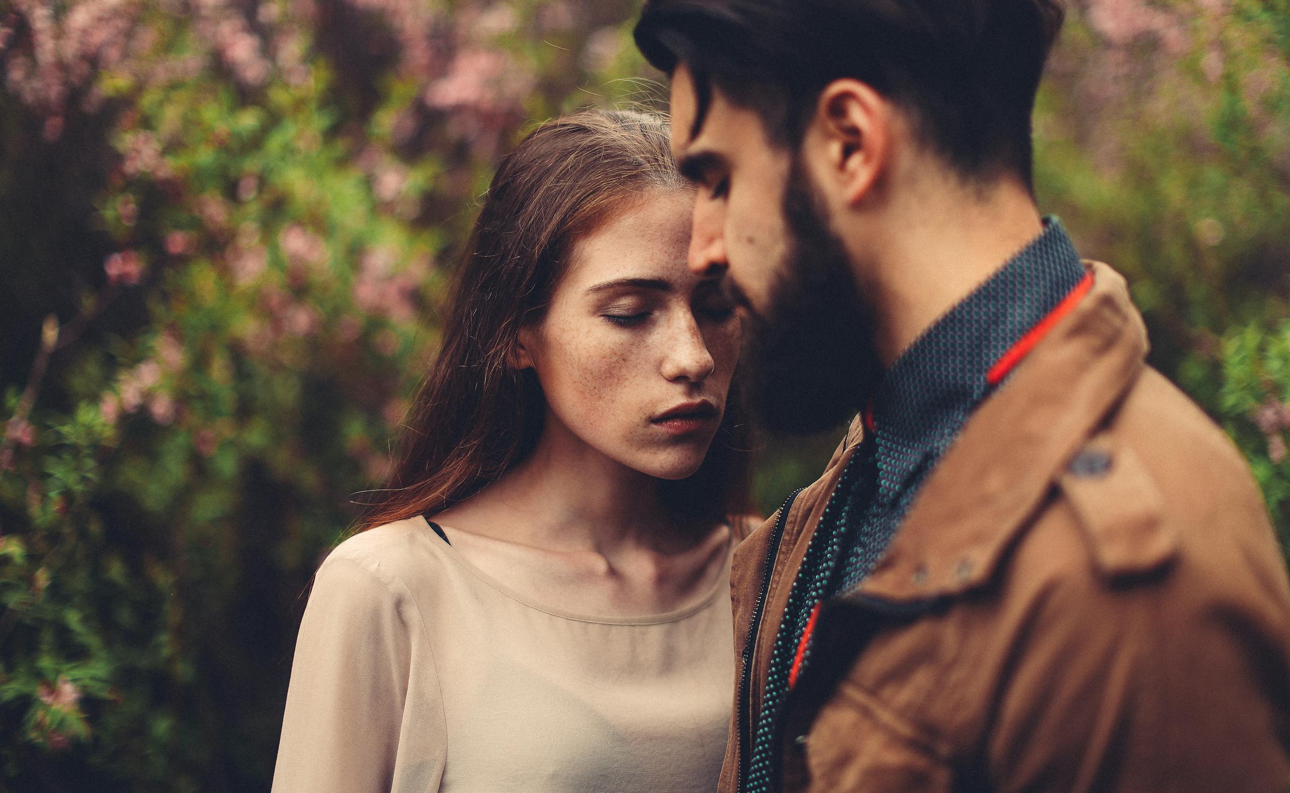 A romantic closeup of a young couple in an outdoor setting, expressing intimacy.