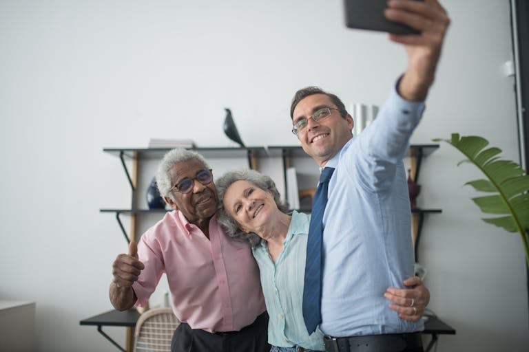 A smiling group of three, including an elderly couple, taking a selfie indoors.
