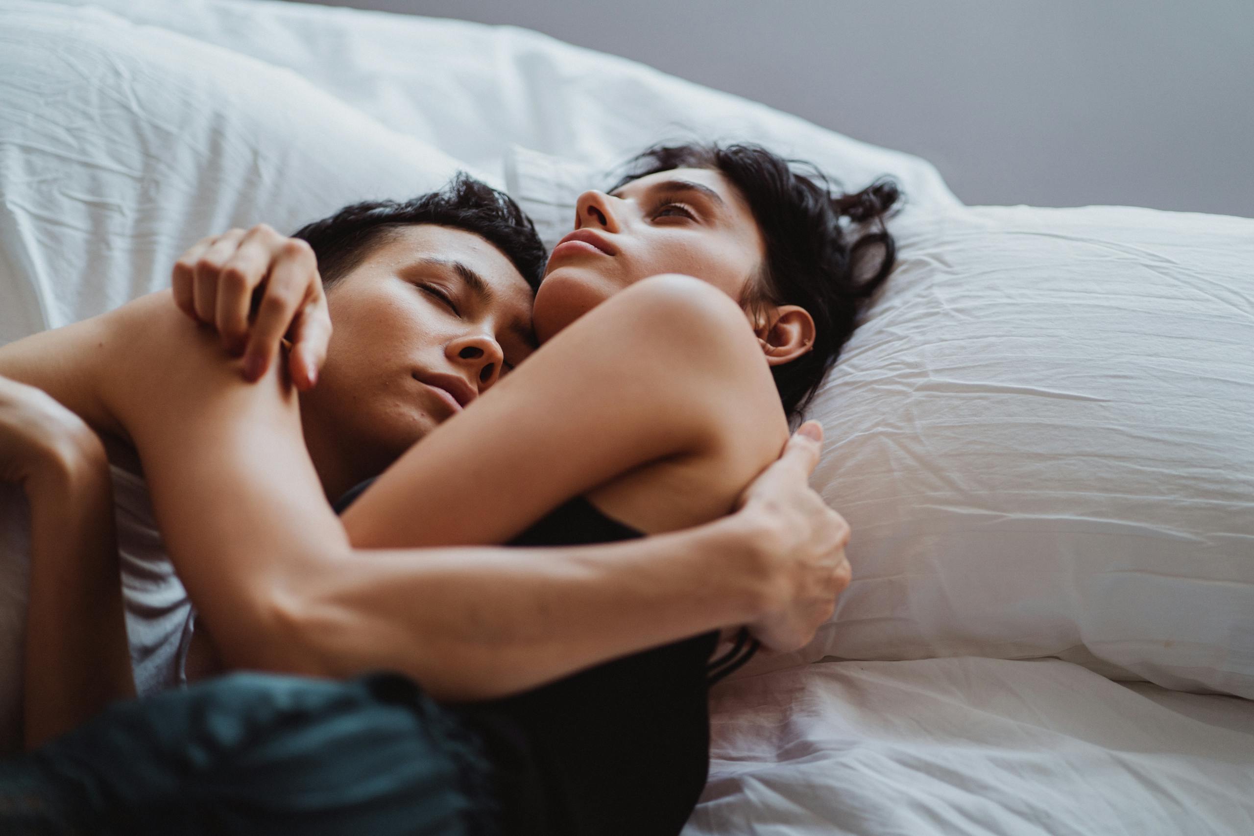 A tender moment of an affectionate couple embracing in bed, capturing warmth and intimacy.