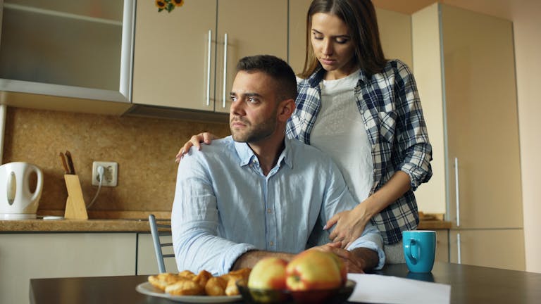 A thoughtful couple shares an emotional moment in a cozy kitchen setting.