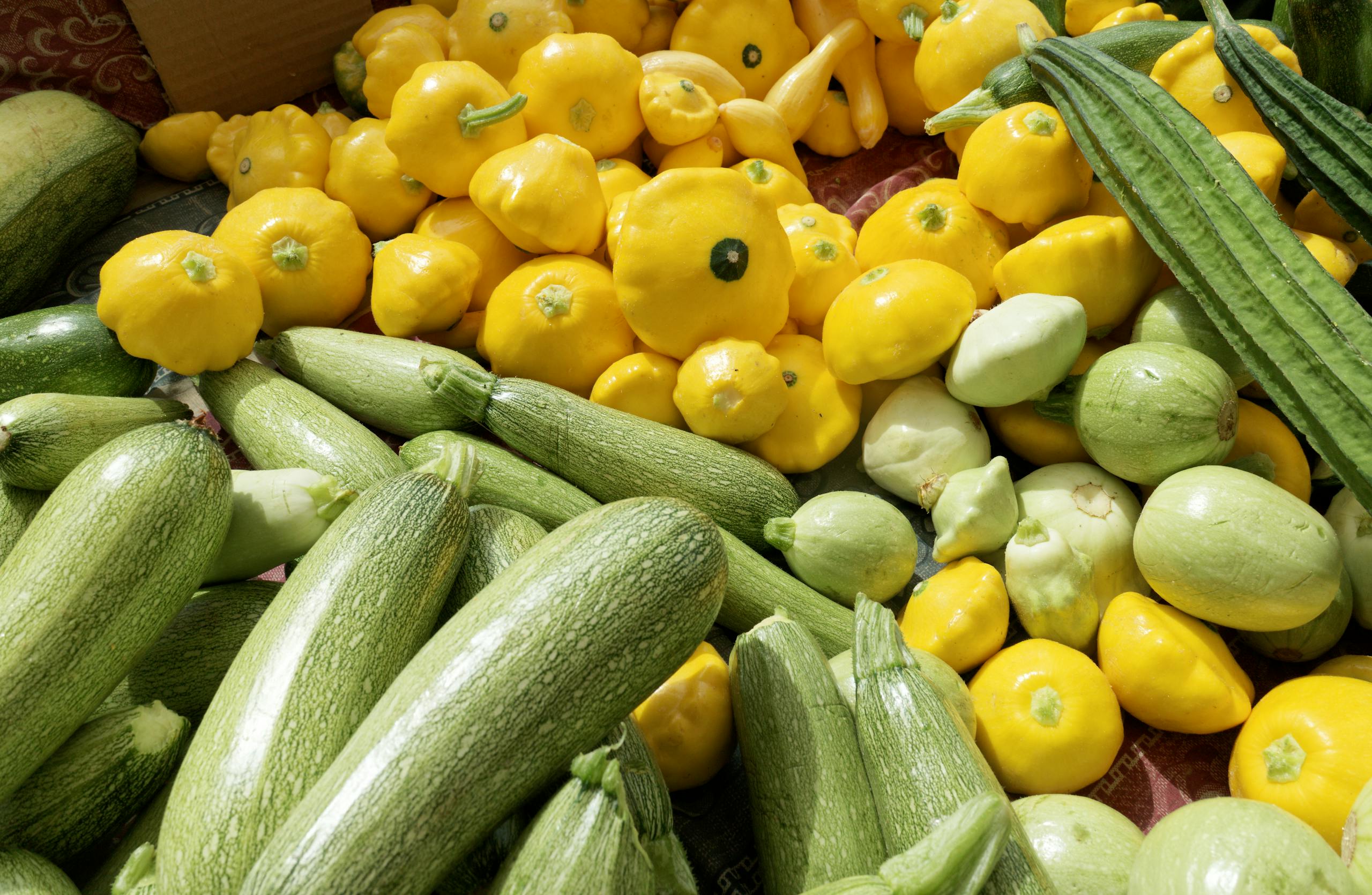 A variety of fresh green and yellow squashes displayed outdoors, perfect for healthy cooking.